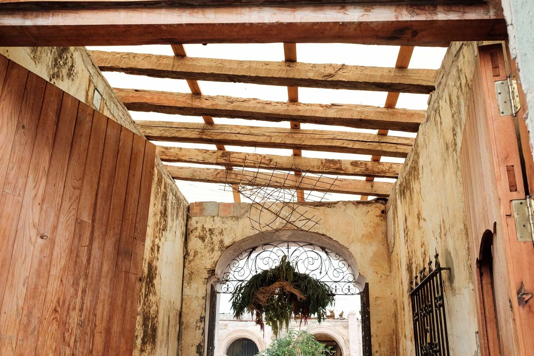 Detailed close-up of a rustic floral entrance arch at Proyecto Murguia showing the beautiful texture and age of the ruin walls.