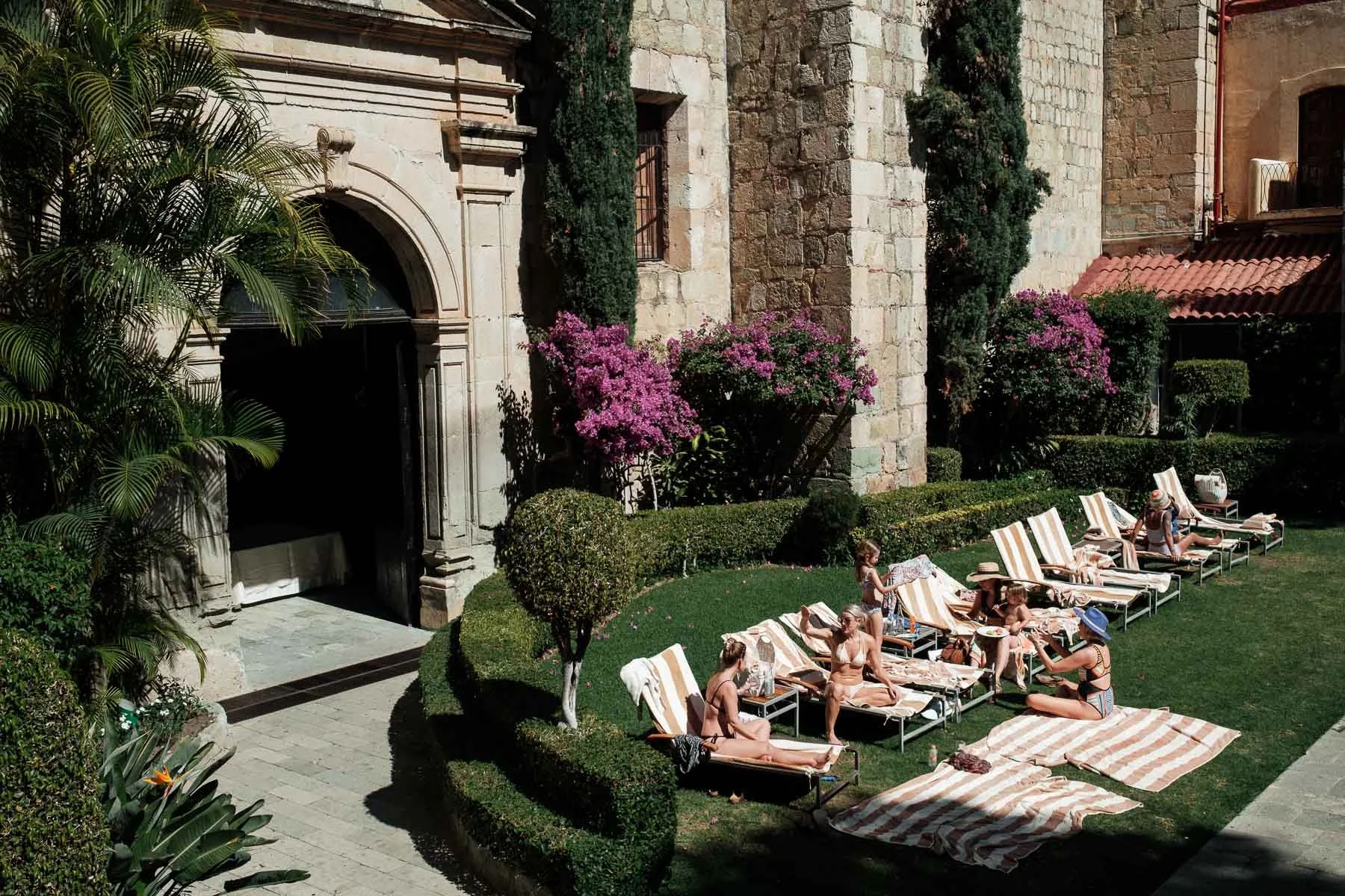 Wedding guests and family relaxing by the pool at Quinta Real Oaxaca, enjoying the sunny hours before the main event.
