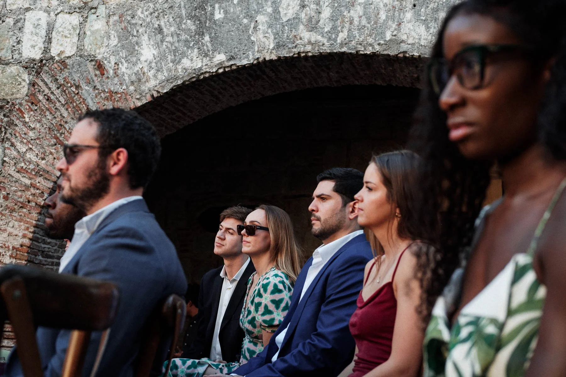 Candid documentary photograph of wedding guests watching the ceremony attentively, capturing the emotional atmosphere at Quinta Real.