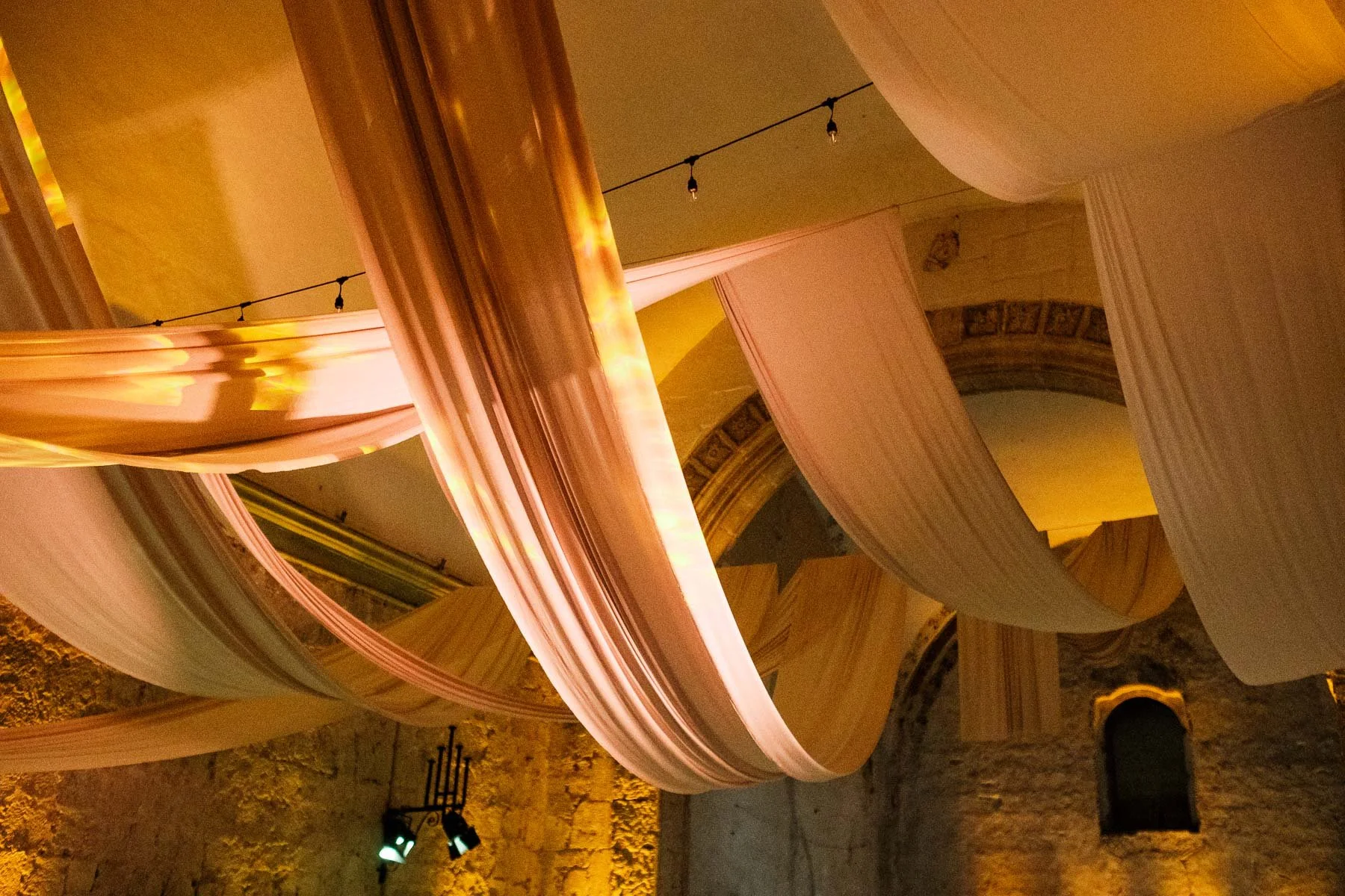 Sophisticated wedding reception decor at Quinta Real featuring draped ceiling fabrics and dramatic lighting for a cinematic party atmosphere.