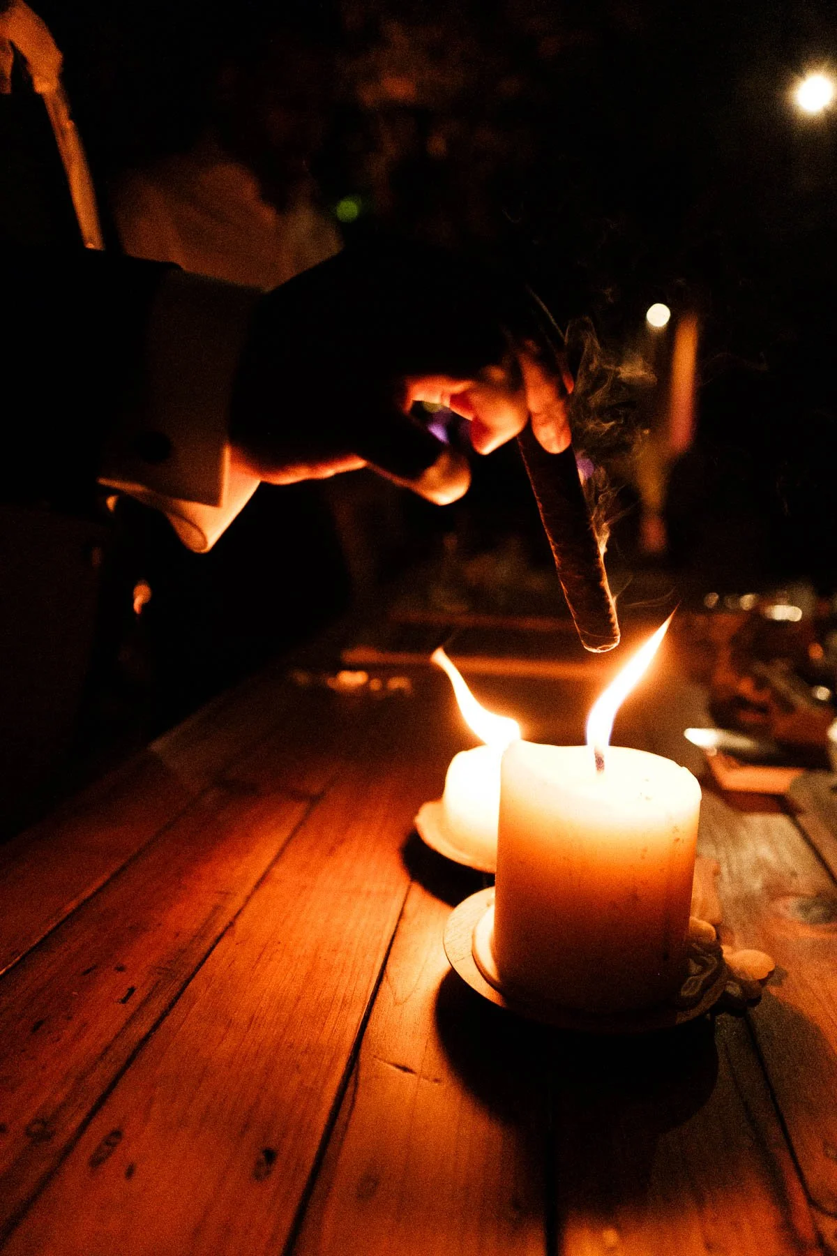 A wedding guest lights a cigar during the reception, capturing the relaxed and celebratory mood at La Fabrica Patio.