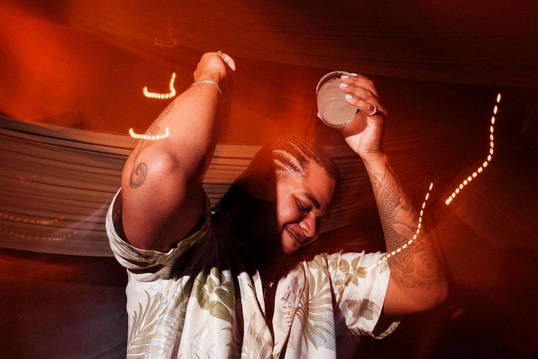 Candid documentary shot of a wedding guest dancing happily with a drink in hand, capturing the vibrant celebration and atmosphere of a reception at Quinta Real Oaxaca.