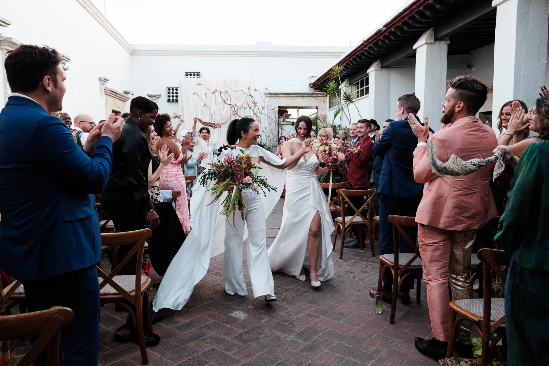 High-energy ceremony exit at Casa Convite with the historic building as a backdrop, capturing the pure joy of the newlyweds.