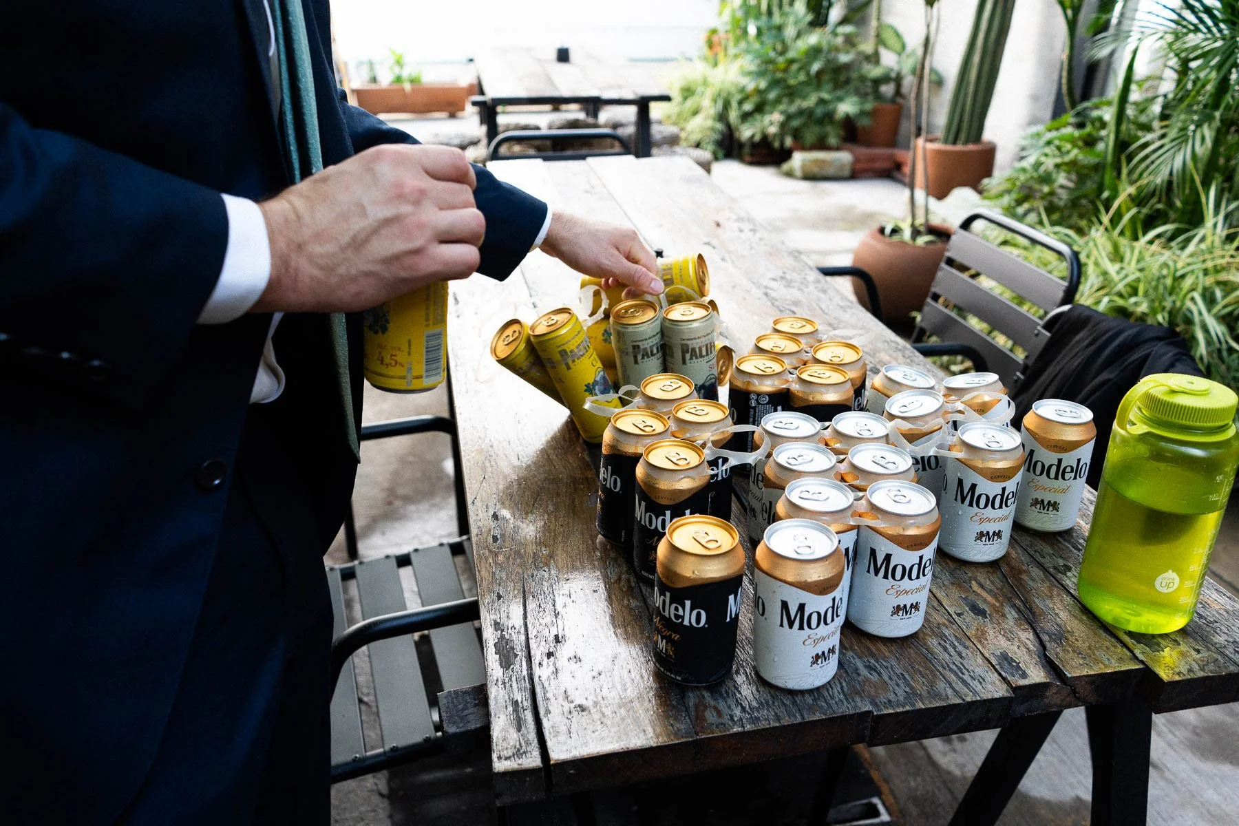 A guest reaching for a beer from a table filled with drinks during the wedding morning.
