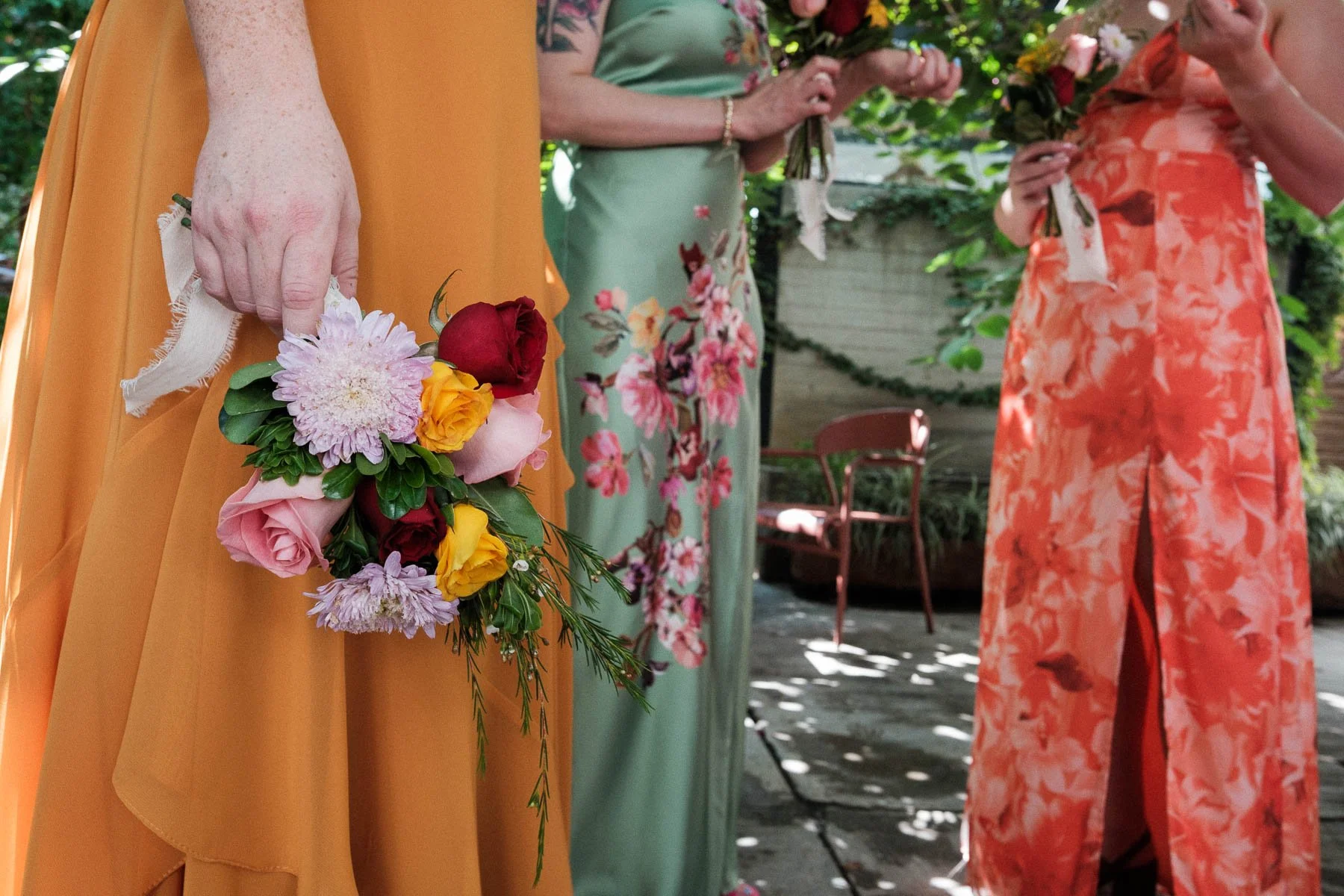 Bridesmaids in vibrant dresses sharing a conversation with their bouquets.