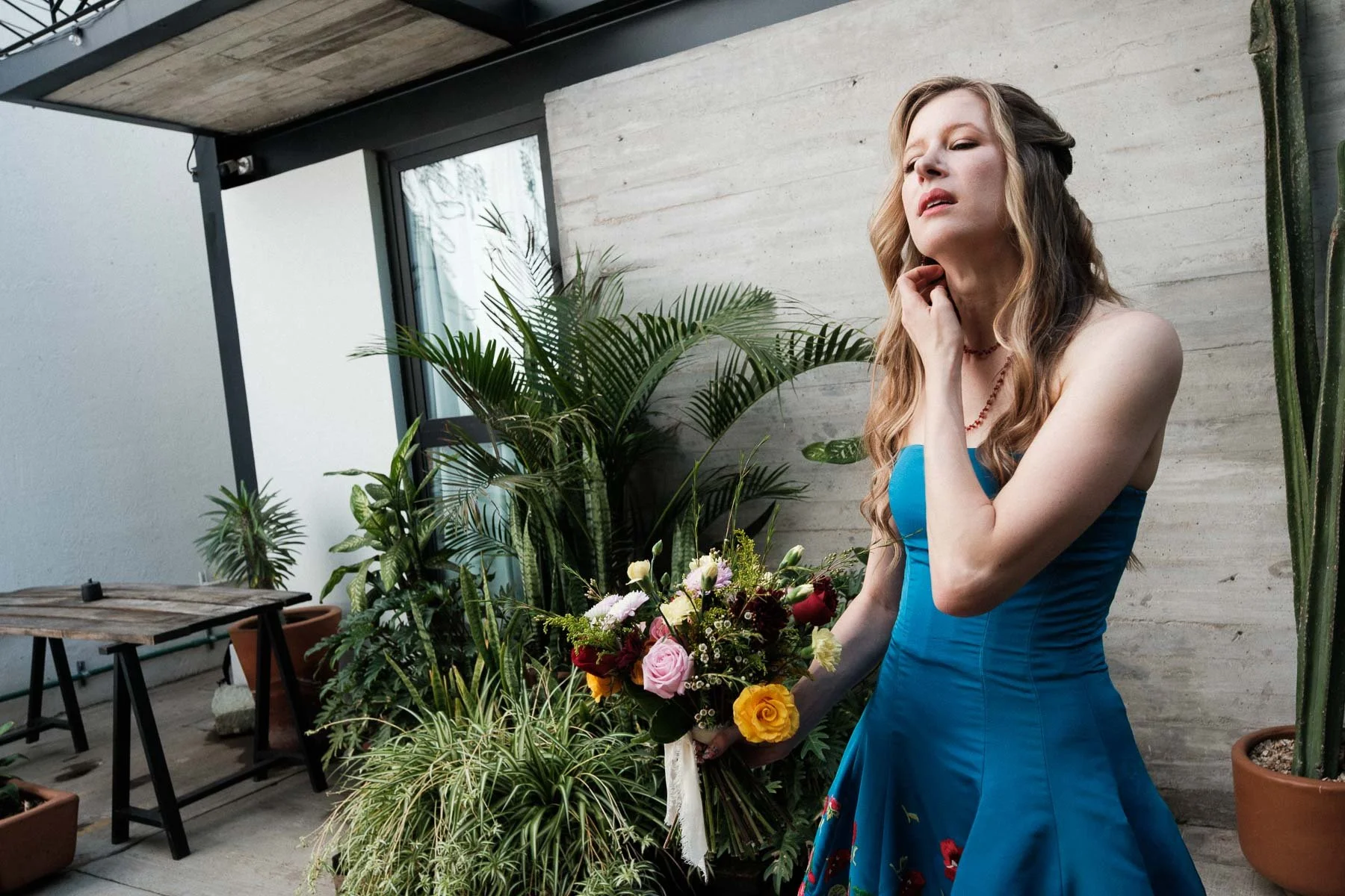 The bride in her blue wedding dress adjusting her hair while holding her bouquet.