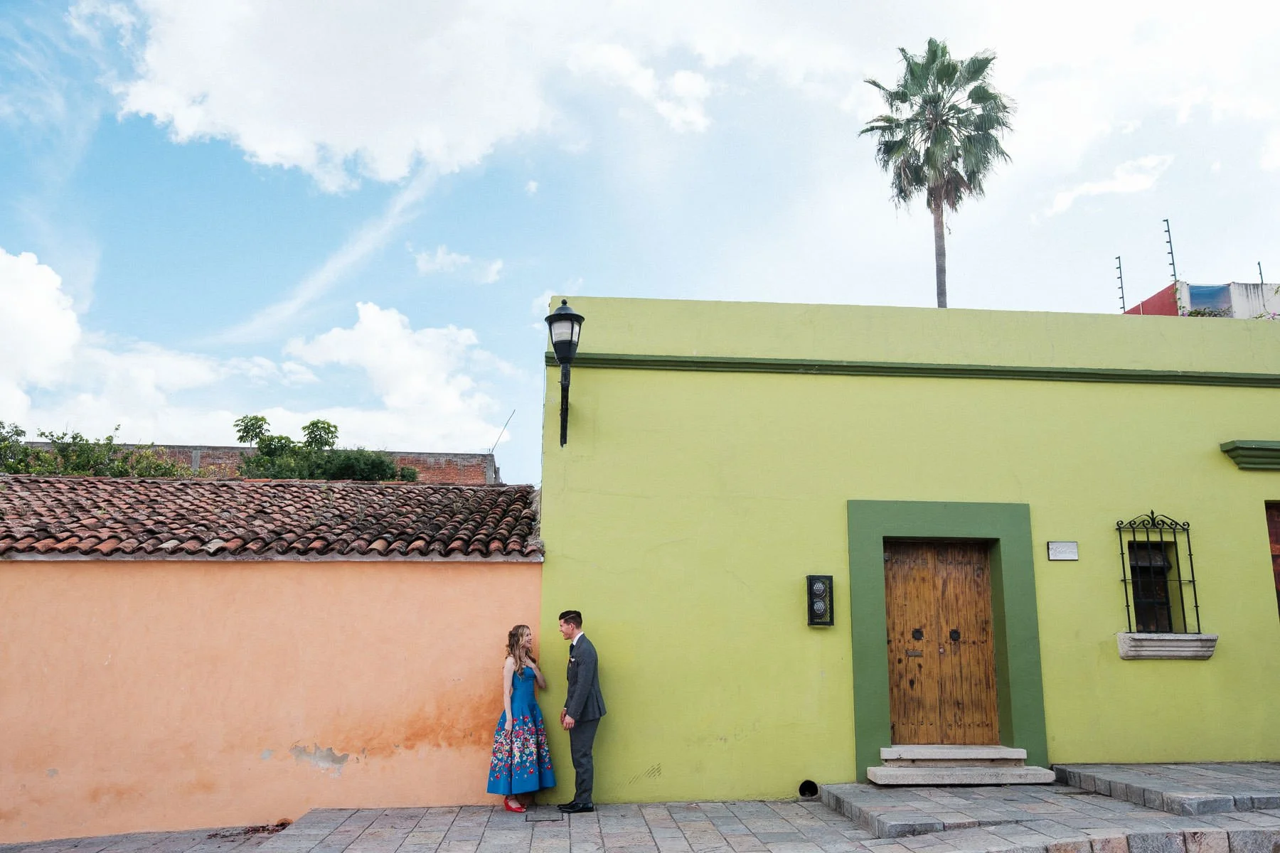 A wide shot capturing the couple chatting, surrounded by the green and orange architecture of the city.