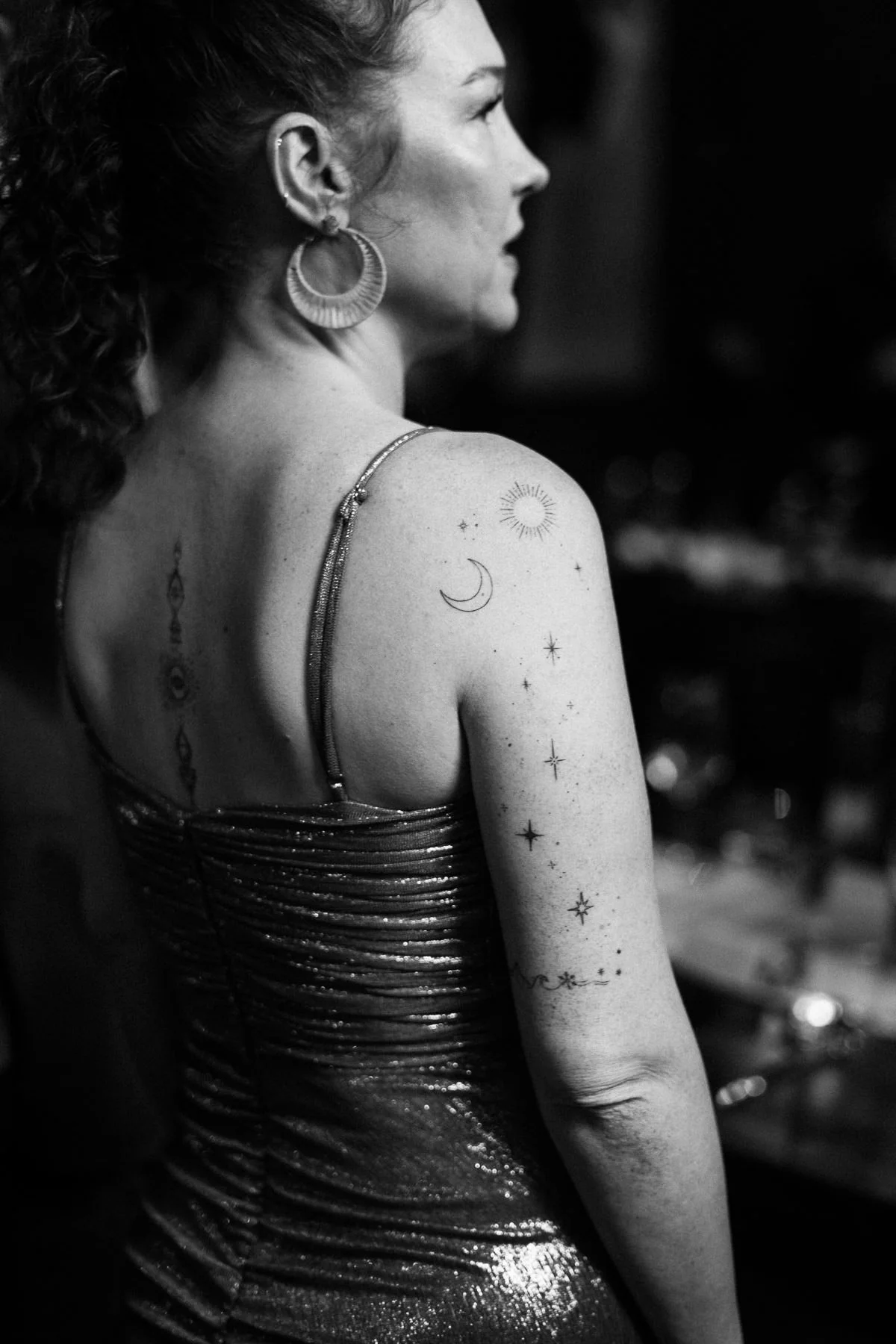A close-up documentary frame of a wedding guest with detailed arm tattoos during the celebration.