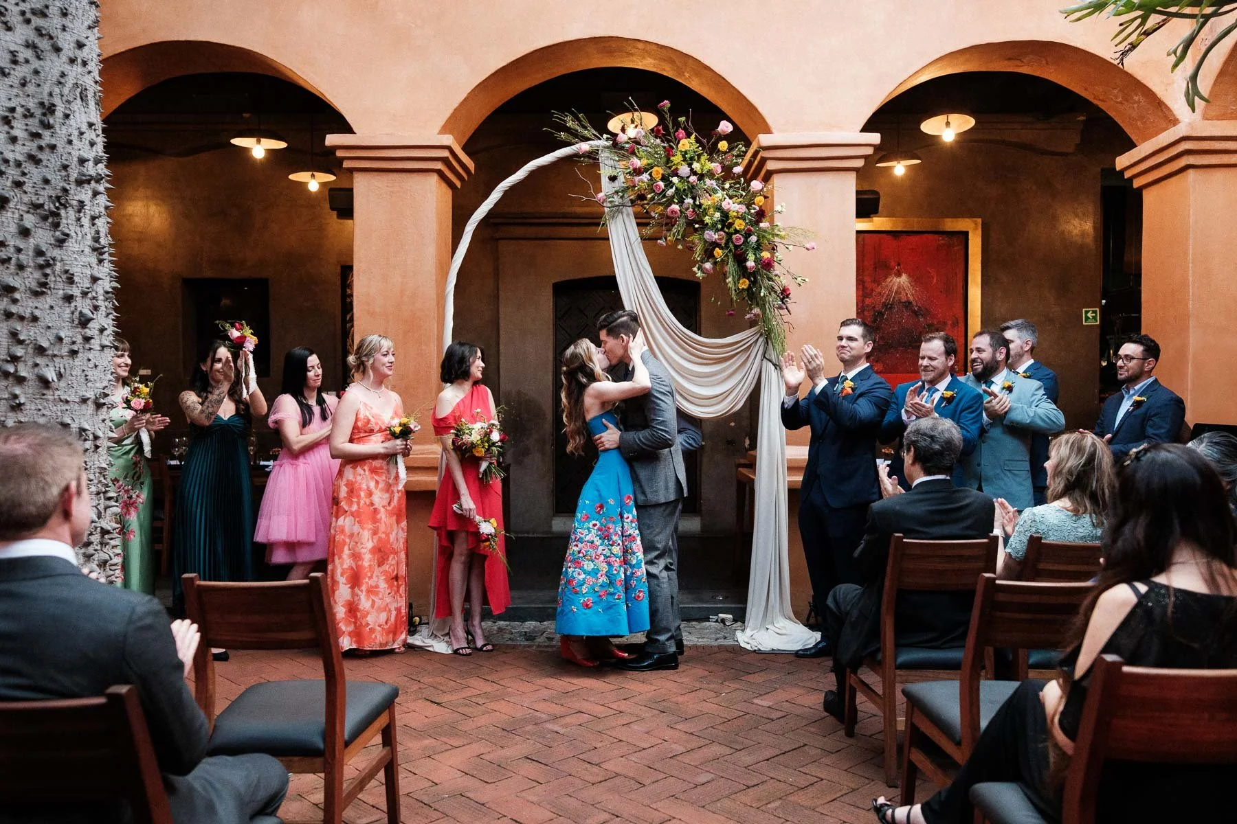 The couple’s first kiss at the end of their intimate ceremony against the orange walls of Asador Bacanora.