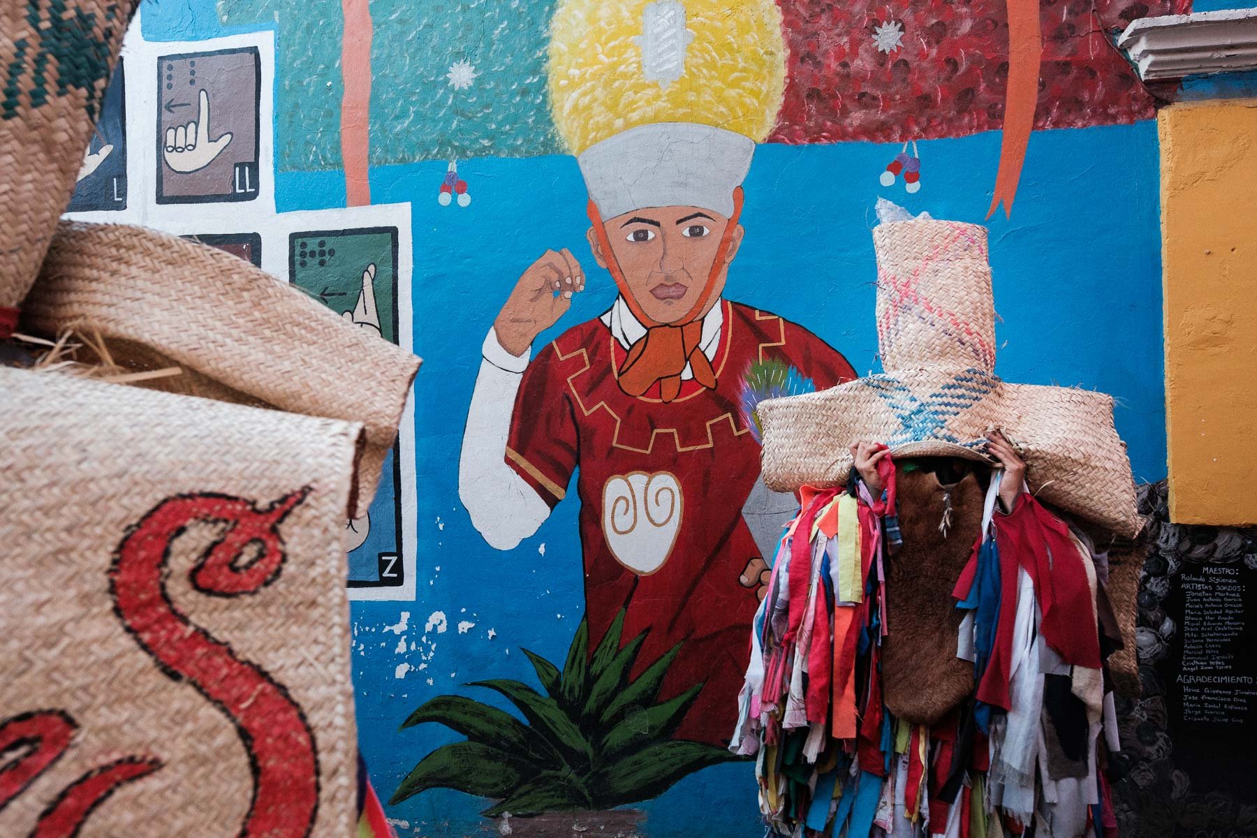 A traditional Calenda character getting ready in front of a street art mural in Jalatlaco, Oaxaca.