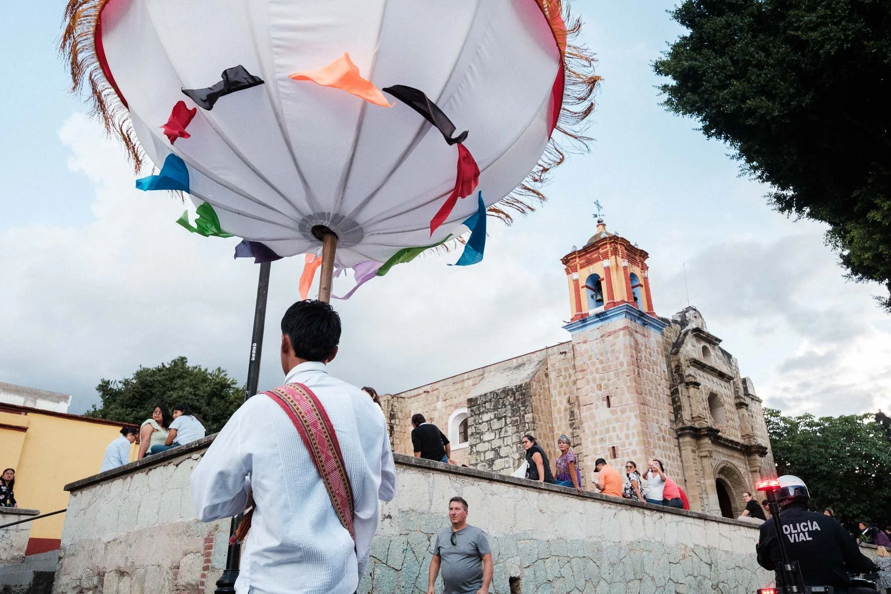 A wide street photography shot of the wedding parade winding through the historic Barrio de Jalatlaco.