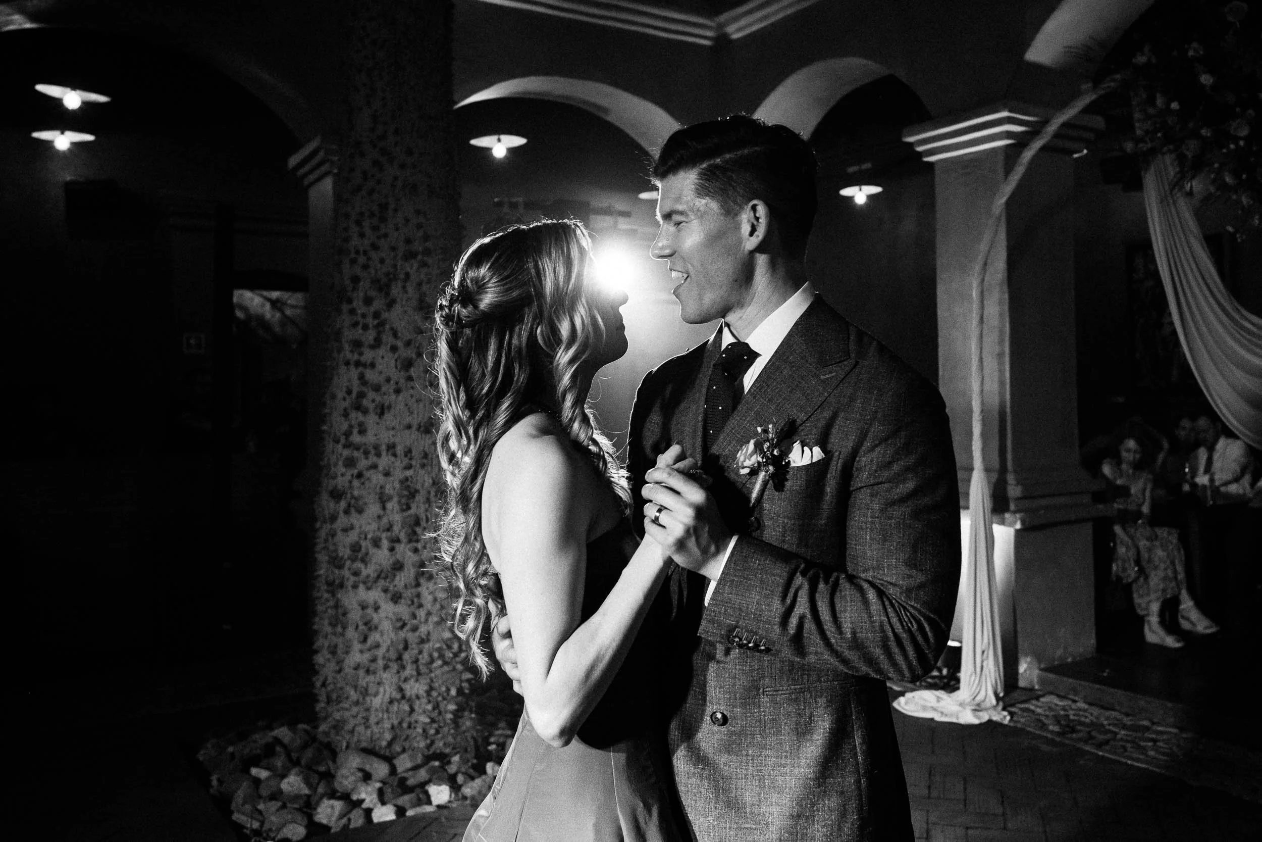 The couple's first dance at Asador Bacanora with dramatic backlighting highlighting their eye contact.