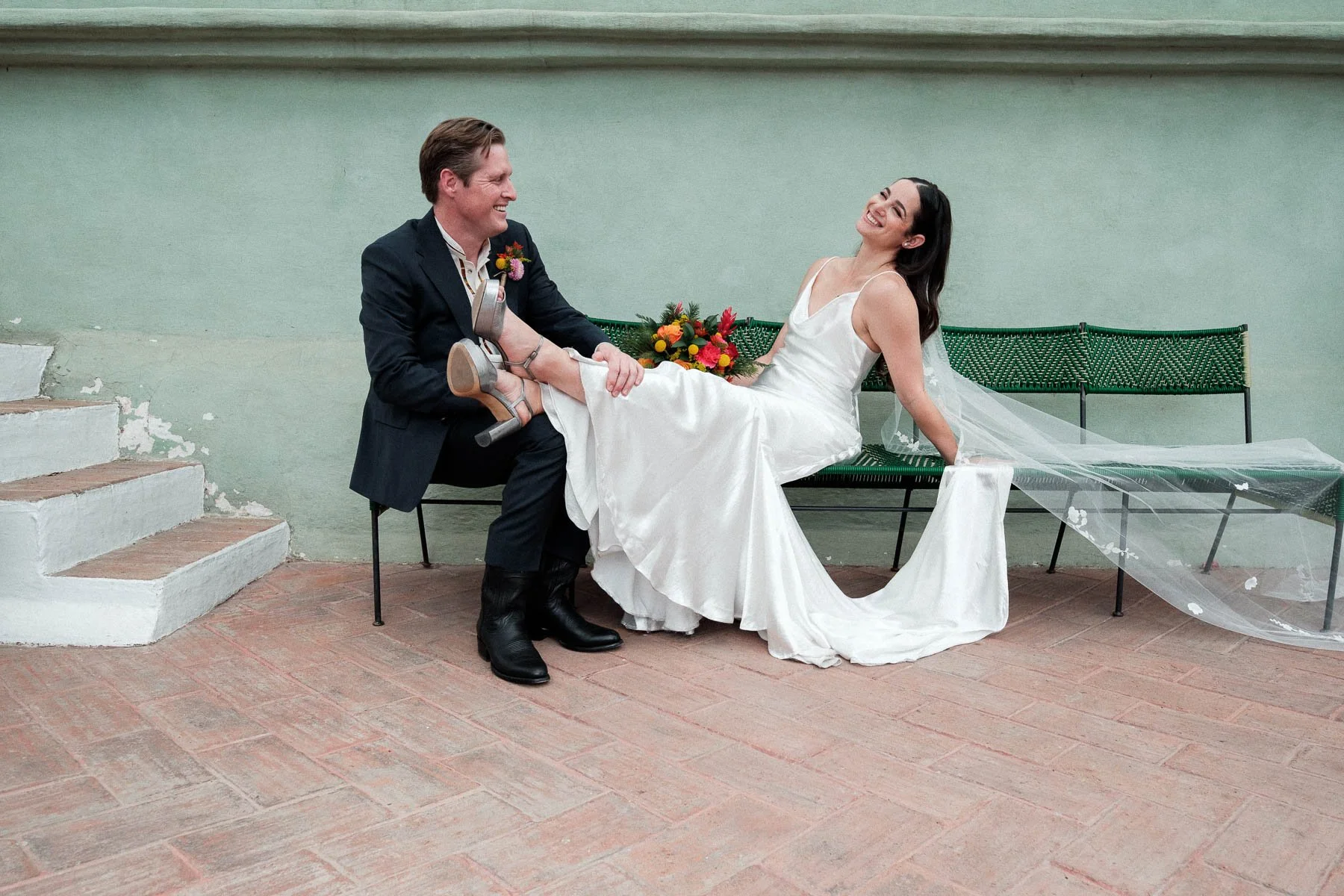 Documentary wedding portrait on a bench at Hotel Casa Oaxaca with a minimalist green wall.