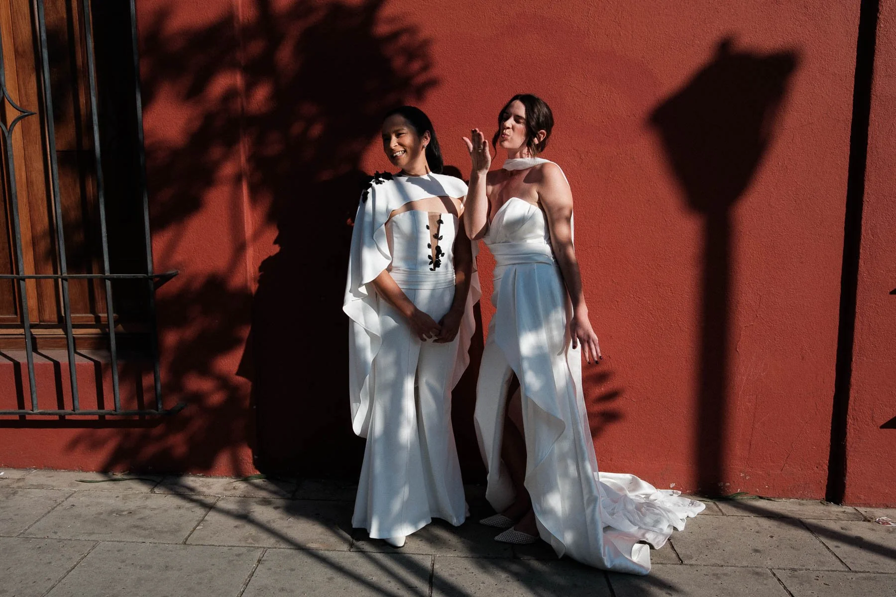 Brides waving to friends across the street, catching a real-life interruption.