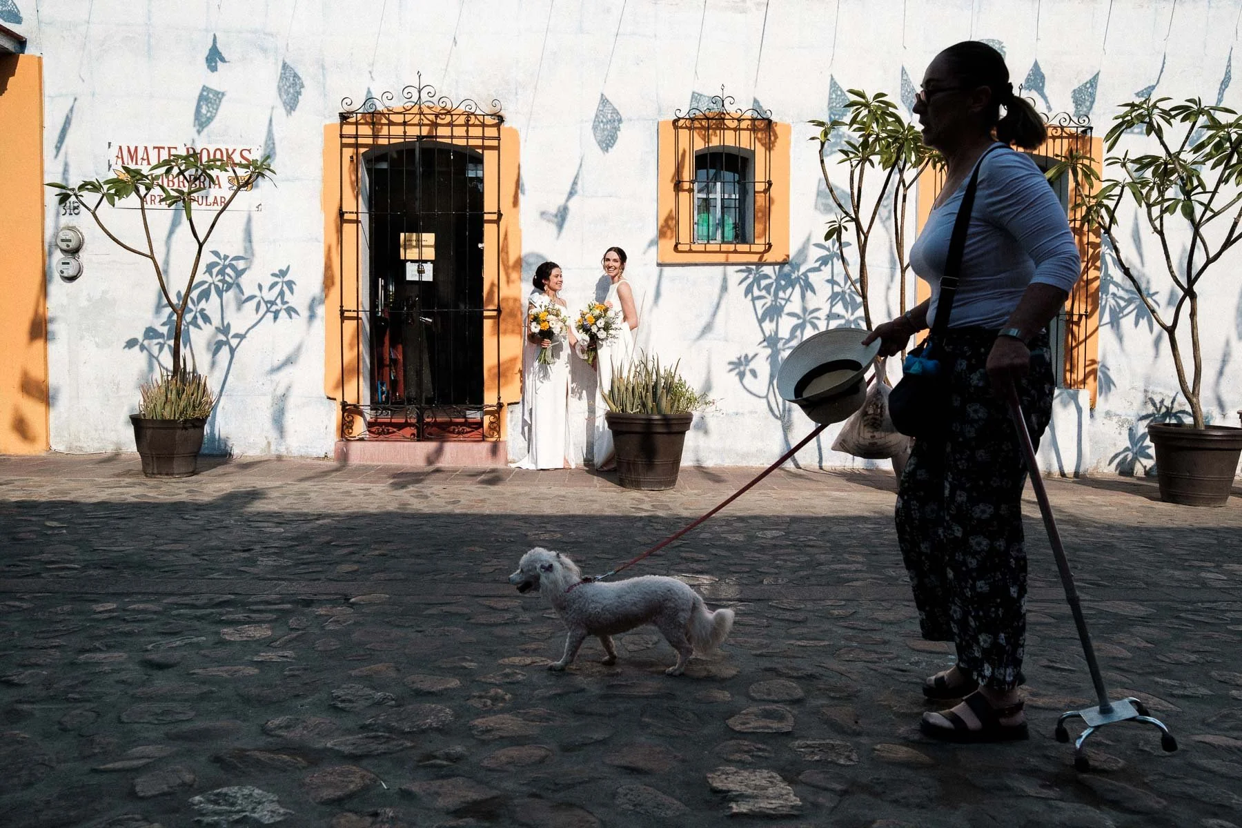 Brides sharing a moment in Jalatlaco while local life passes by in the foreground.