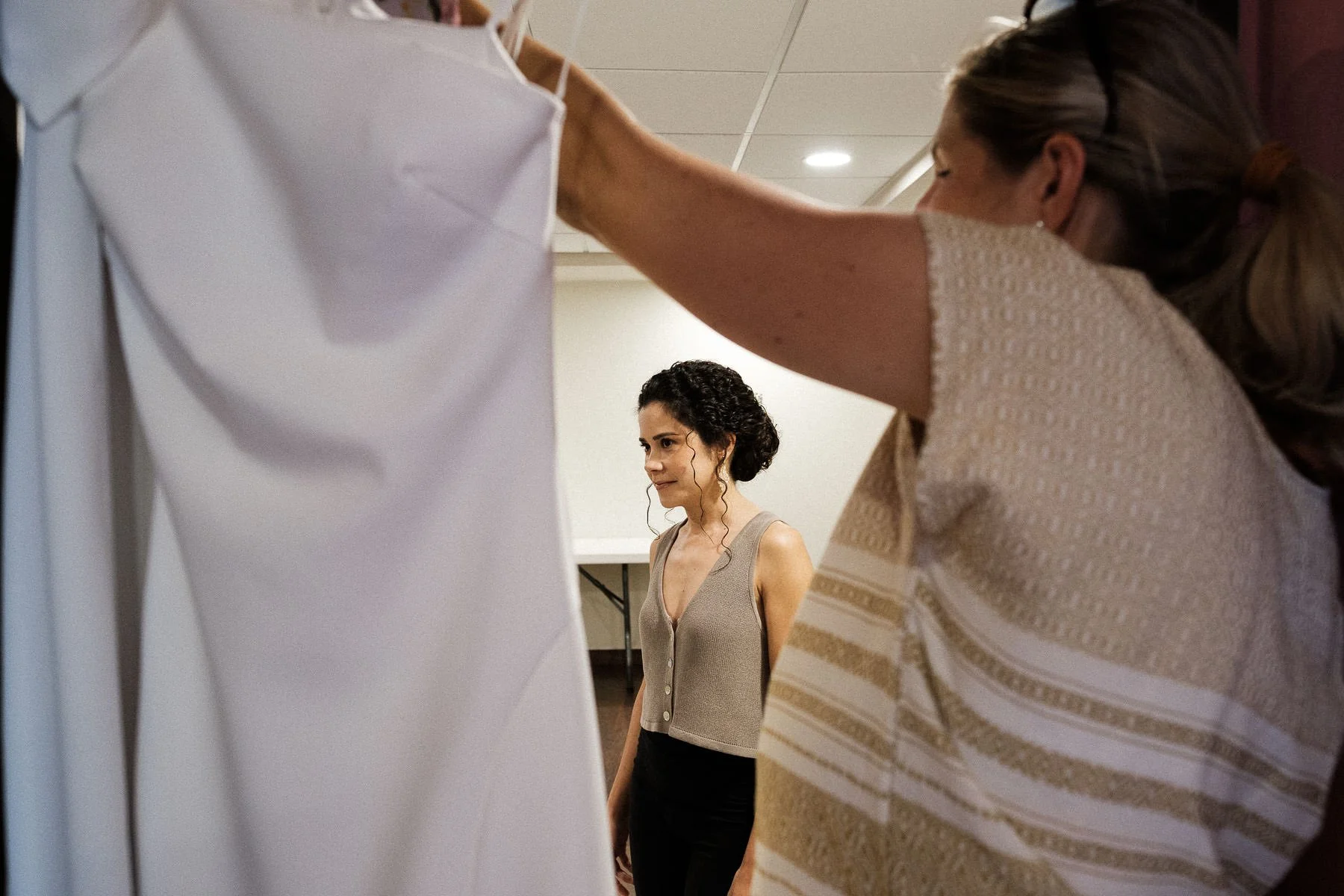 Candid composition of a bride getting ready framed by her wedding planner.