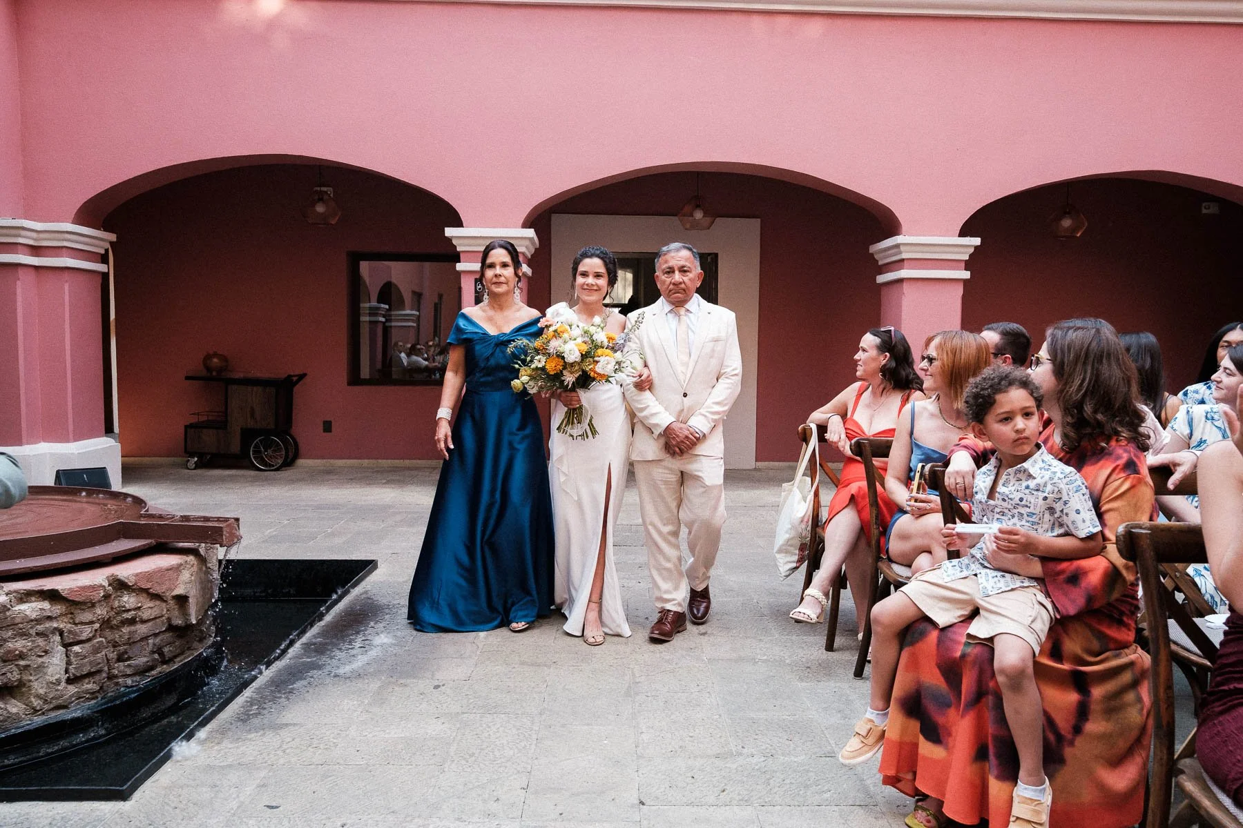 Bride walking down the aisle with her parents at Hotel City Centro.
