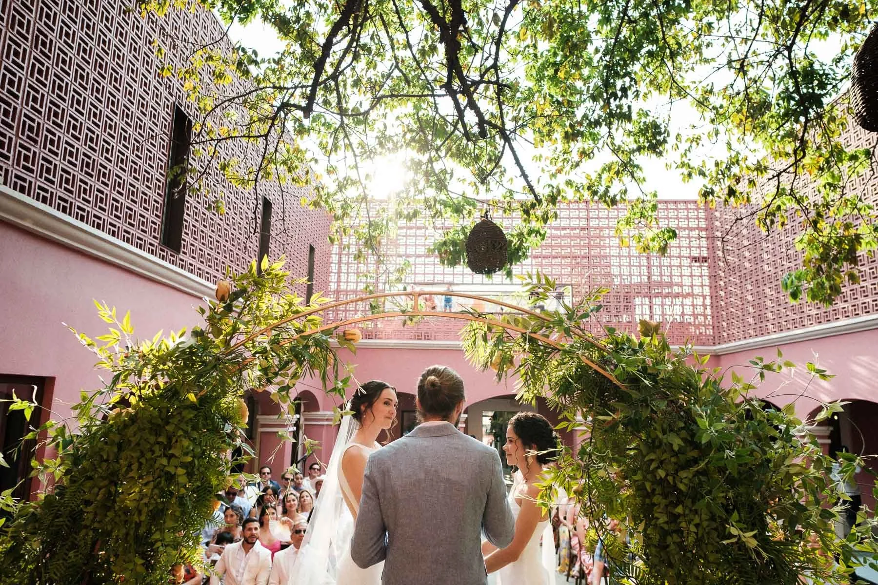 Wide angle shot of the ceremony, the brides, and the architecture of Hotel City Centro.