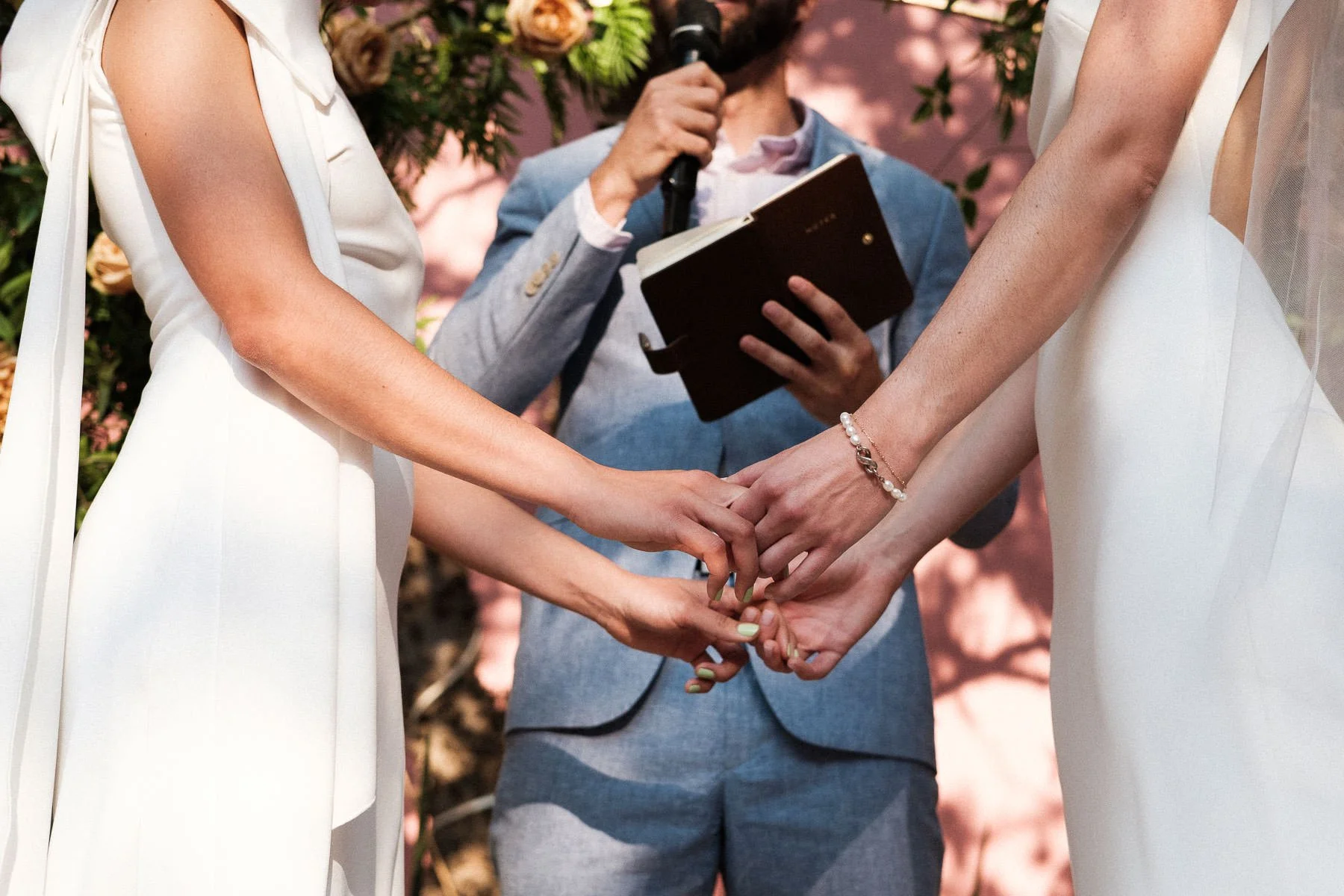Close-up of the brides holding hands while listening to the officiant.