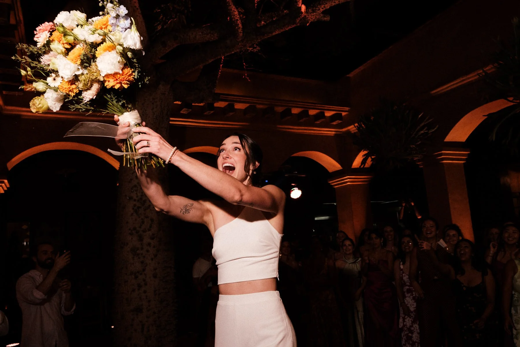 The bride tossing her wedding bouquet to the guests.