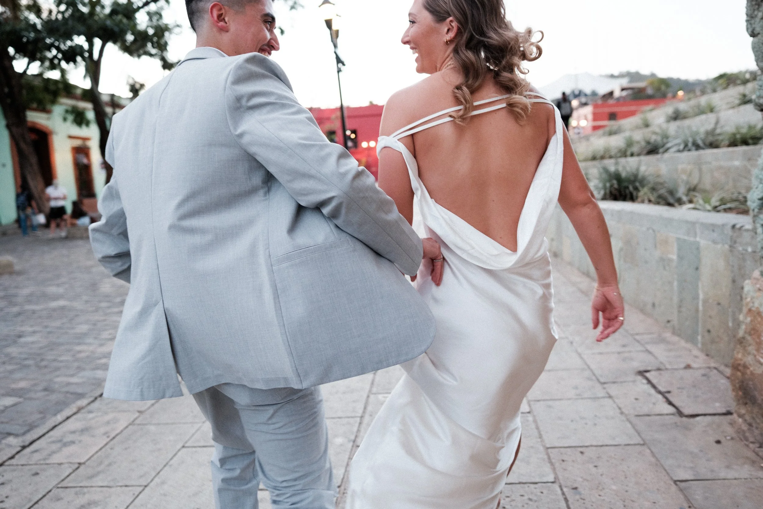 Elopement couple walking through the streets of Oaxaca, smiling at each other.