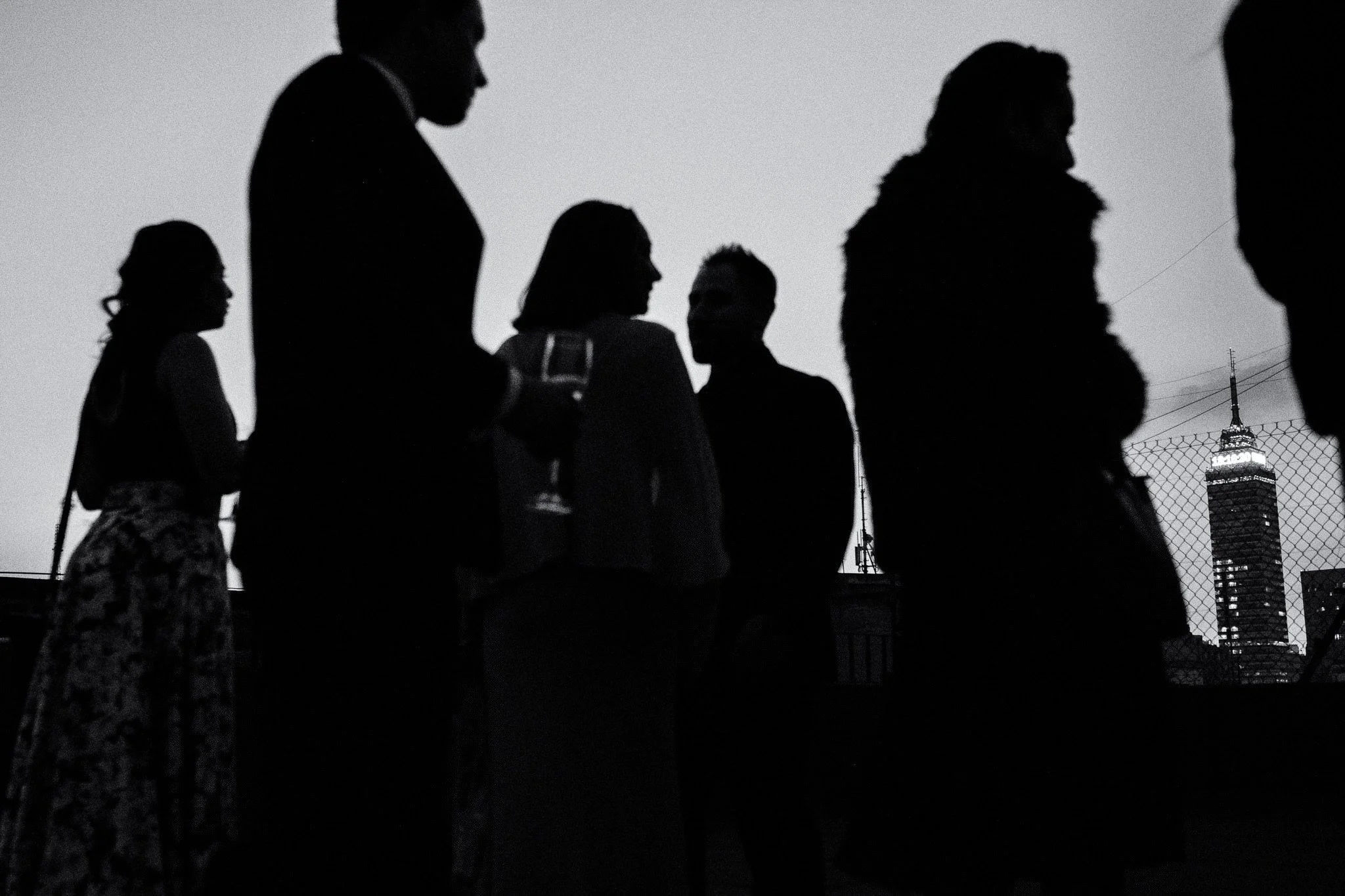 Mexico City wedding photographer Lucca Lazzarini, capturing silhouetted guests and the Torre Latinoamericana during a cocktail hour.