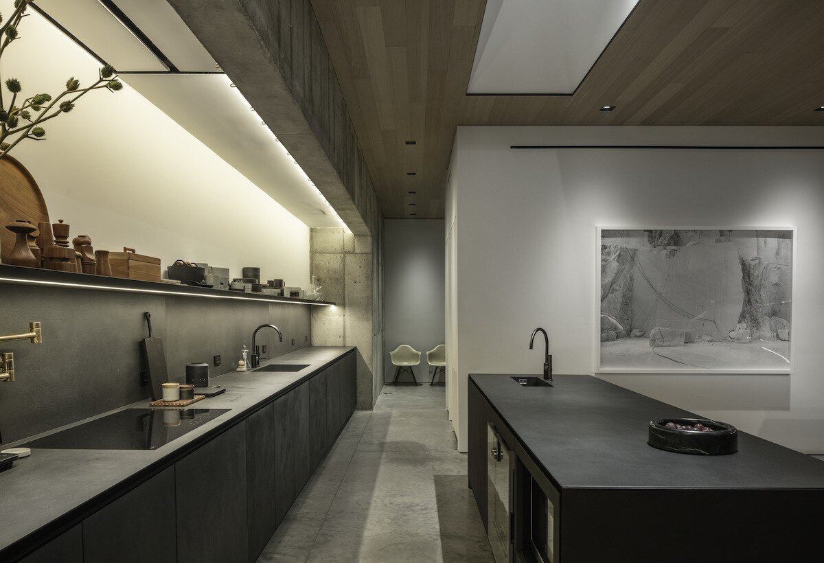 the-kitchen-showcases-the-firms-signature-style-integrating-concrete-and-darker-materials-softened-by-light-colored-wood-to-warm-the-space.jpg