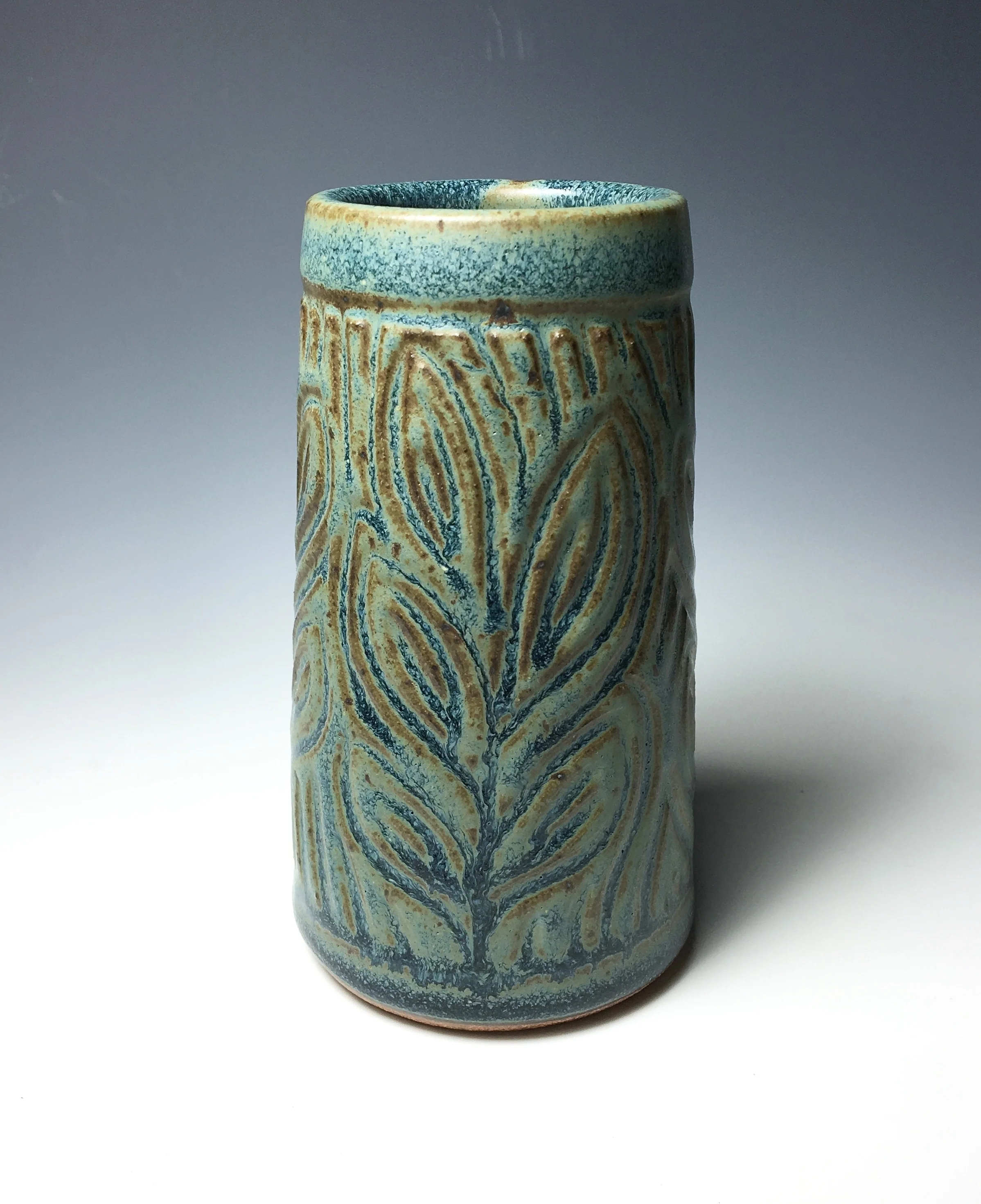 Small bud vase. Approximately five inches tall. Textured Blue Glaze. Incised leaf motif.