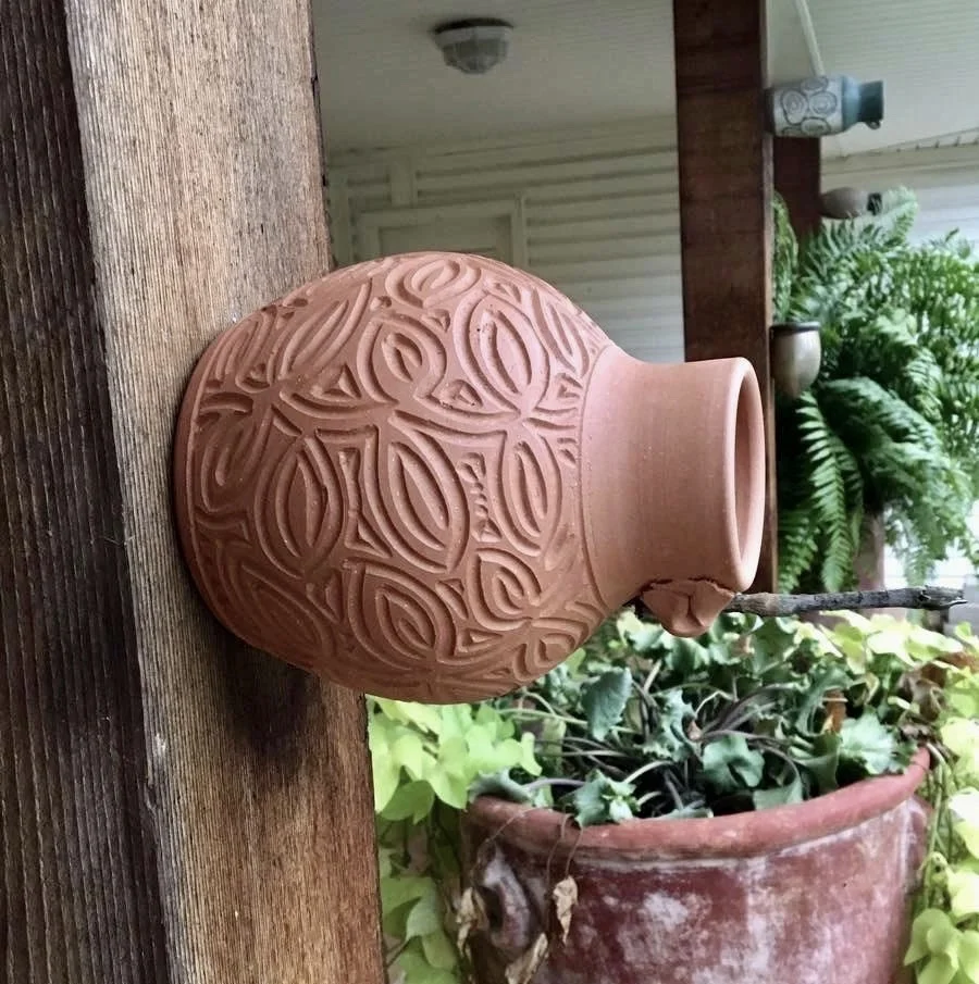 Terra Cotta Bird bottle with leaf pattern carved freehand. Measures approximately nine inches by six inches.