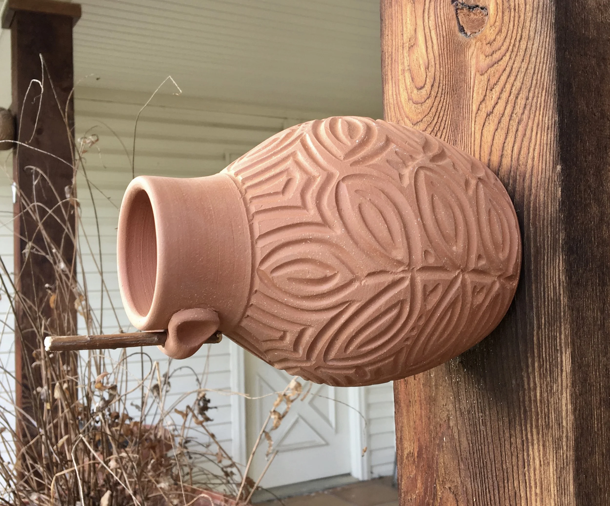Terra cotta bird bottle with leaf pattern carved freehand. Measures approximately nine inches long with a six inch diameter.