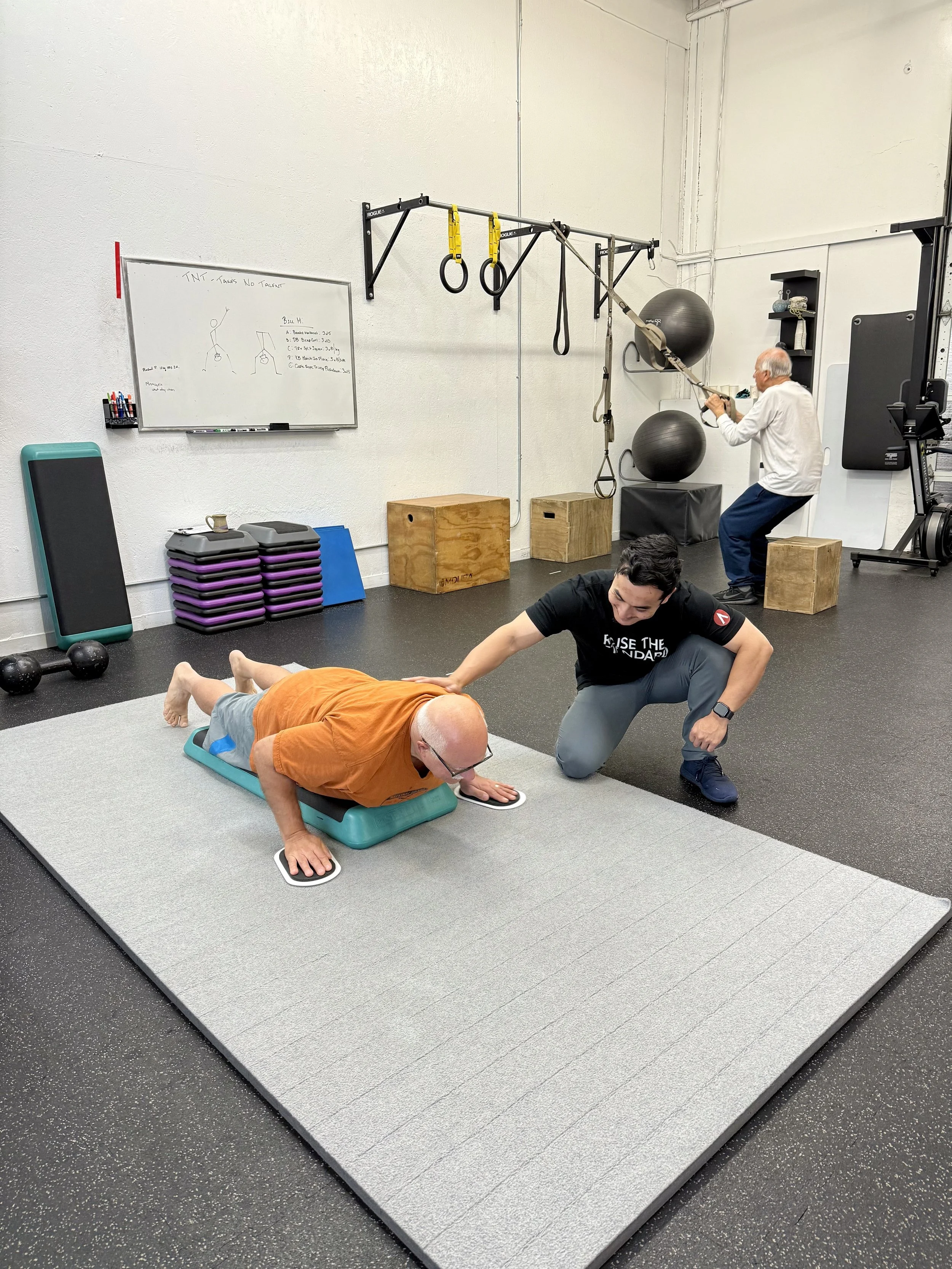 A coach guides a client through a floor exercise at Elevate Health & Performance.