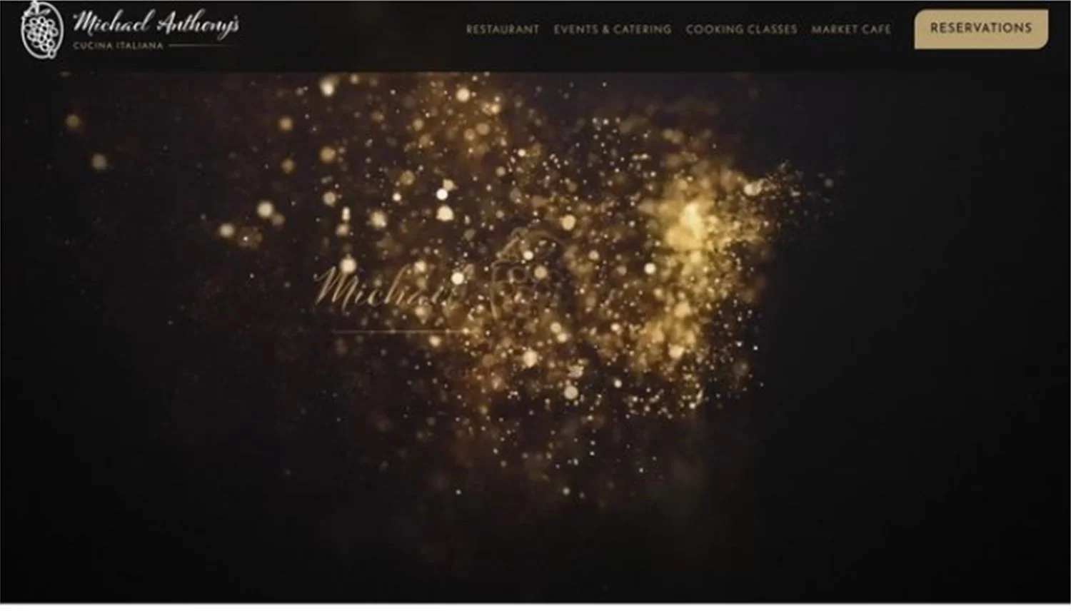 Screenshot of the website Michael Anthony's Cucina Italiana featuring a dark background with golden sparkles. Navigation menu includes options for Restaurant, Events & Catering, Cooking Classes, Market Cafe, and Reservations. The restaurant's logo with a grape cluster icon is in the top left corner.