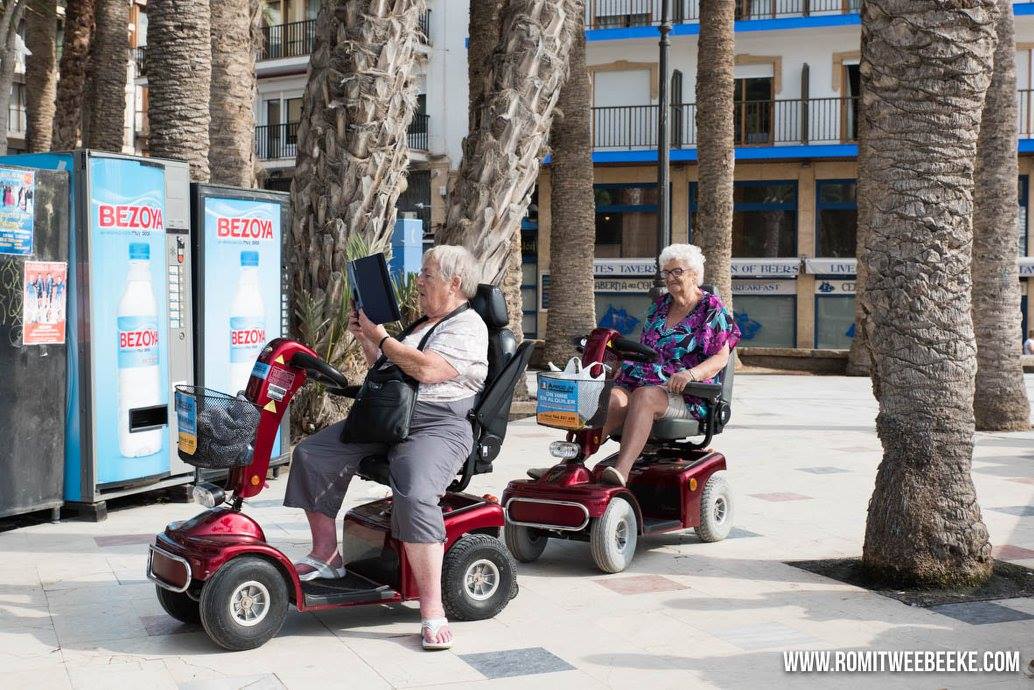 B E N I D O R M - D A G 4 Ondanks dat de gemiddelde leeftijd hier hoger ligt, valt de grote hoeveelheid smartphones en tablets mij ook hier weer op. Er is door de gemeente Benidorm zelfs een wi-fi netwerk aangelegd langs en op de stranden. Veel mensen liggen dus op het strand met een tablet in hun handen of maken een kiekje met hun smartphone voor het thuisfront. Deze twee dames zijn samen op pad met een gehuurde scootmobiel. Ze spreken Engels en komen hier al jaren. Kibbelen d legde de een de ander uit hoe de tablet werkt. Ze proberen namelijk een foto van de hier beroemde witte duiven te maken. Na deze uitleg volgt de uitvoering, waar de ander geduldig op wacht.
