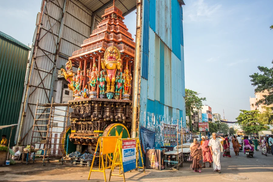 A goporua (an ornate temple tower), with wheels for parades, undergoes maintenance in preparation for an upcoming festival.