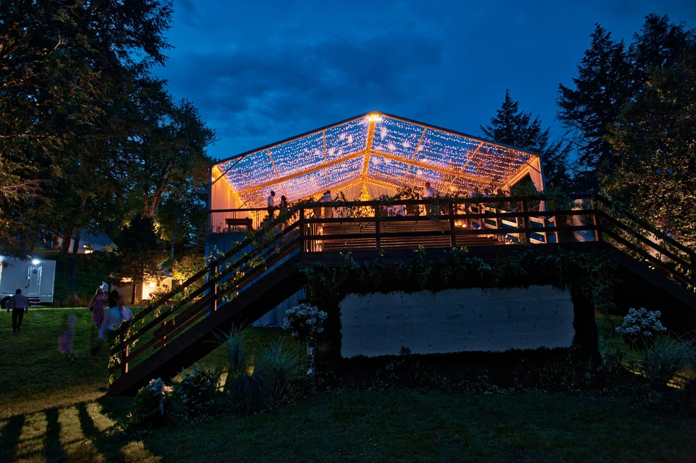 Clear-top tent lit at blue hour on a raised deck