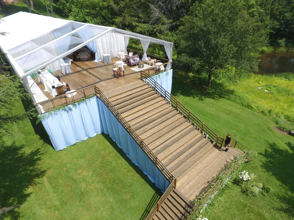 Aerial view of a clear-top tent built over a raised deck and staircase