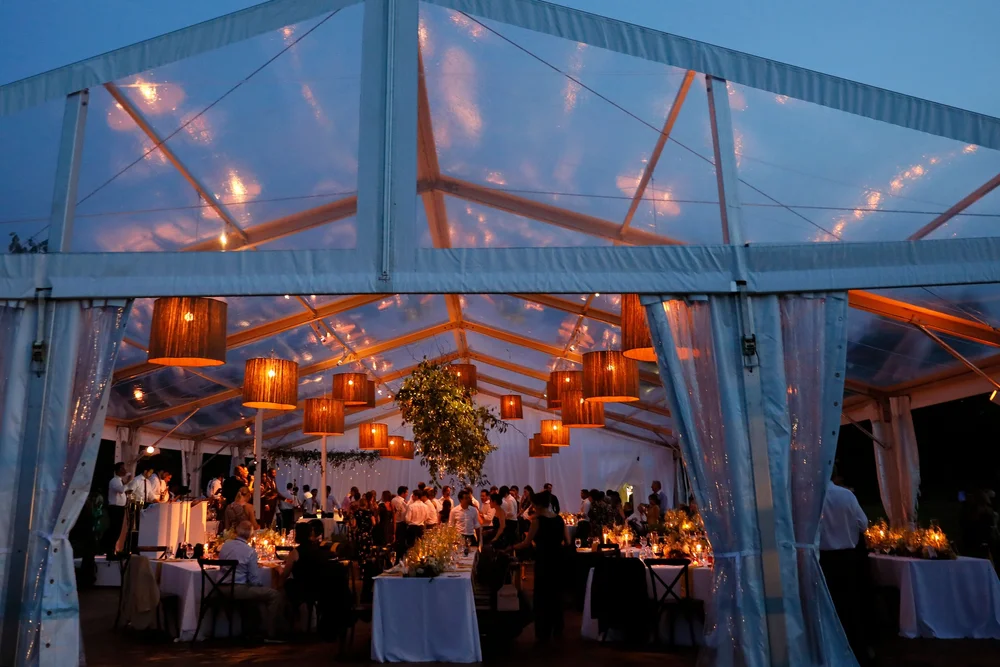 Guests seated at dusk inside a clear-top tent