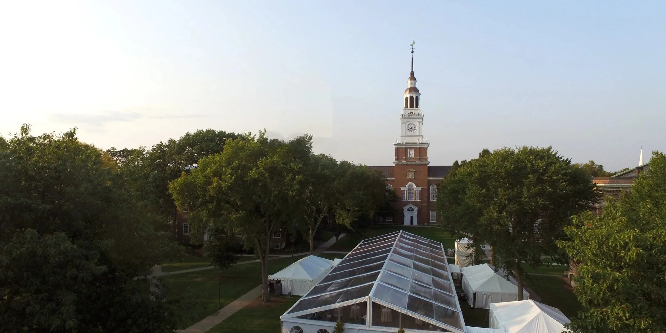 Clear-top event tent on the Dartmouth College green in Hanover, NH, with Baker Library tower behind it