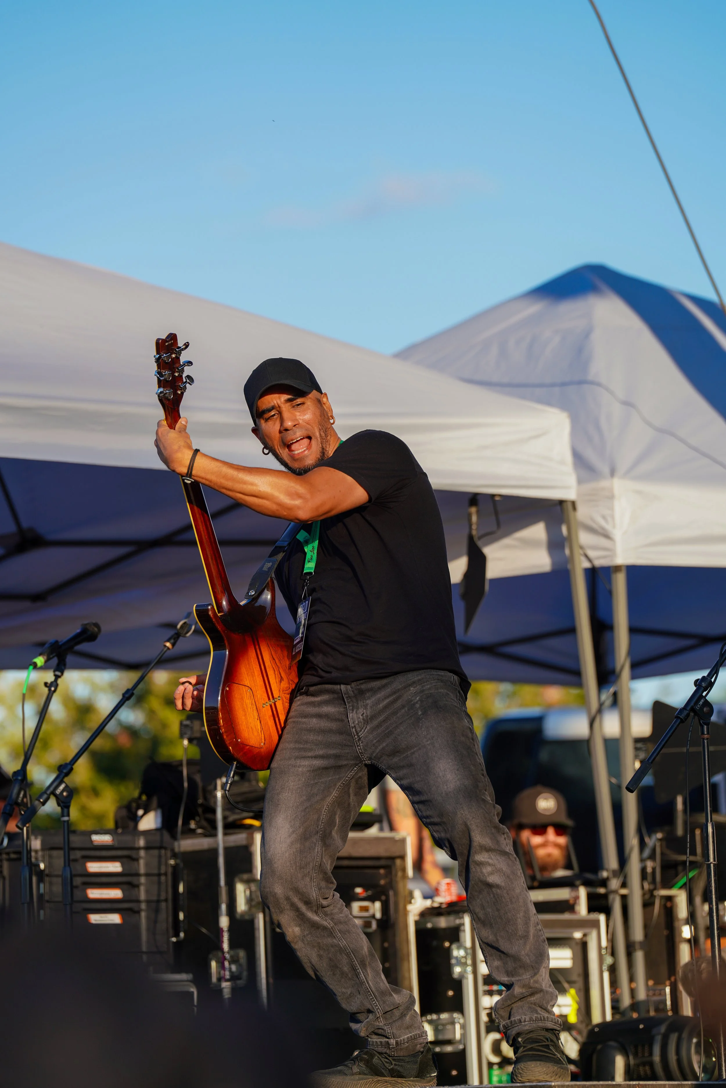 Khris Glaring performing energetically on an outdoor stage with electric guitar