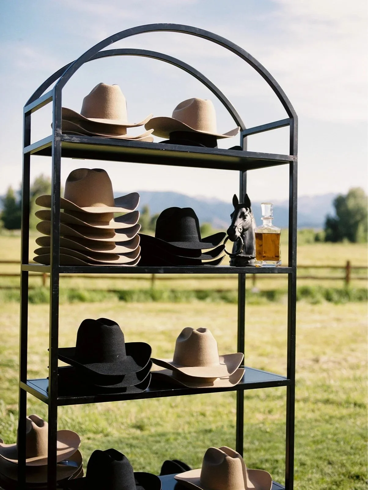 A curated display of cowboy hats invites guests to personalize their own Western-inspired accessories during a luxury wedding welcome party at River Bottoms Ranch in Utah. This interactive guest experience was thoughtfully planned and designed by Mic