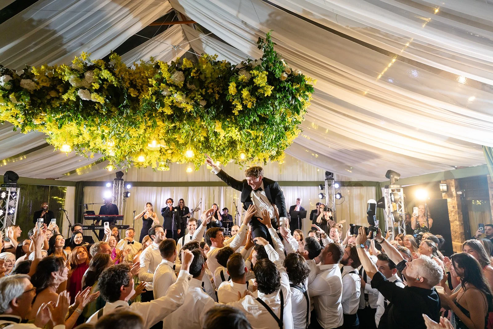 Wedding guests celebrating together on a packed dance floor during a lively reception