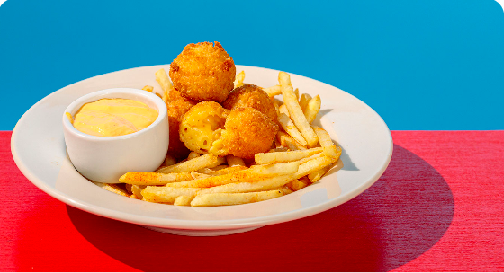 Linus’s Mac and Cheese Bites over French Fries, served with a Spicy Aioli