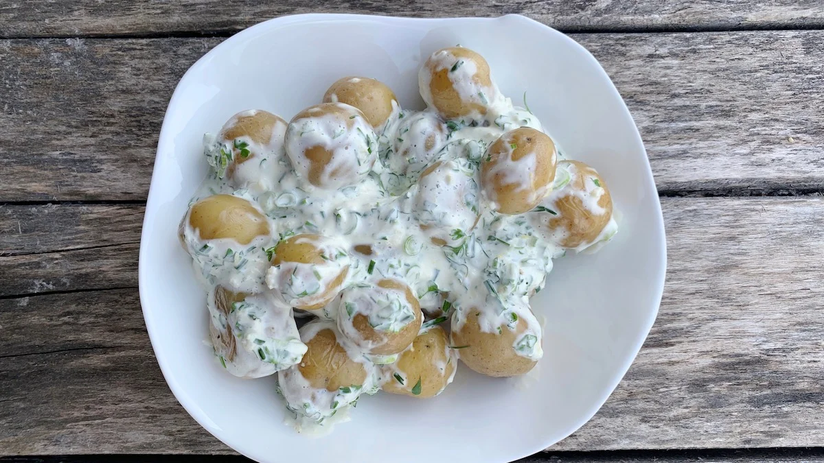 En syrlig potetsalat med creme fraiche, urter og sitronskall smaker nydelig til grillmat.