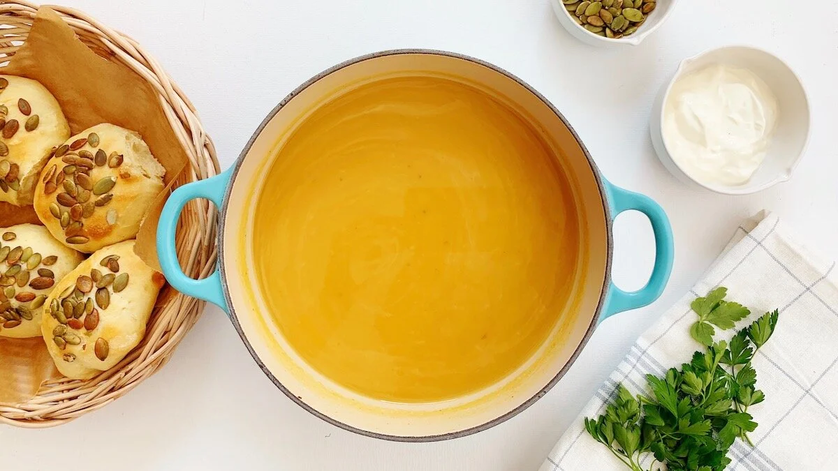 Ovnsbakt gresskarsuppe serveres med ferske rundstykker, en liten rømmeklatt og ristede gresskarkjerner.