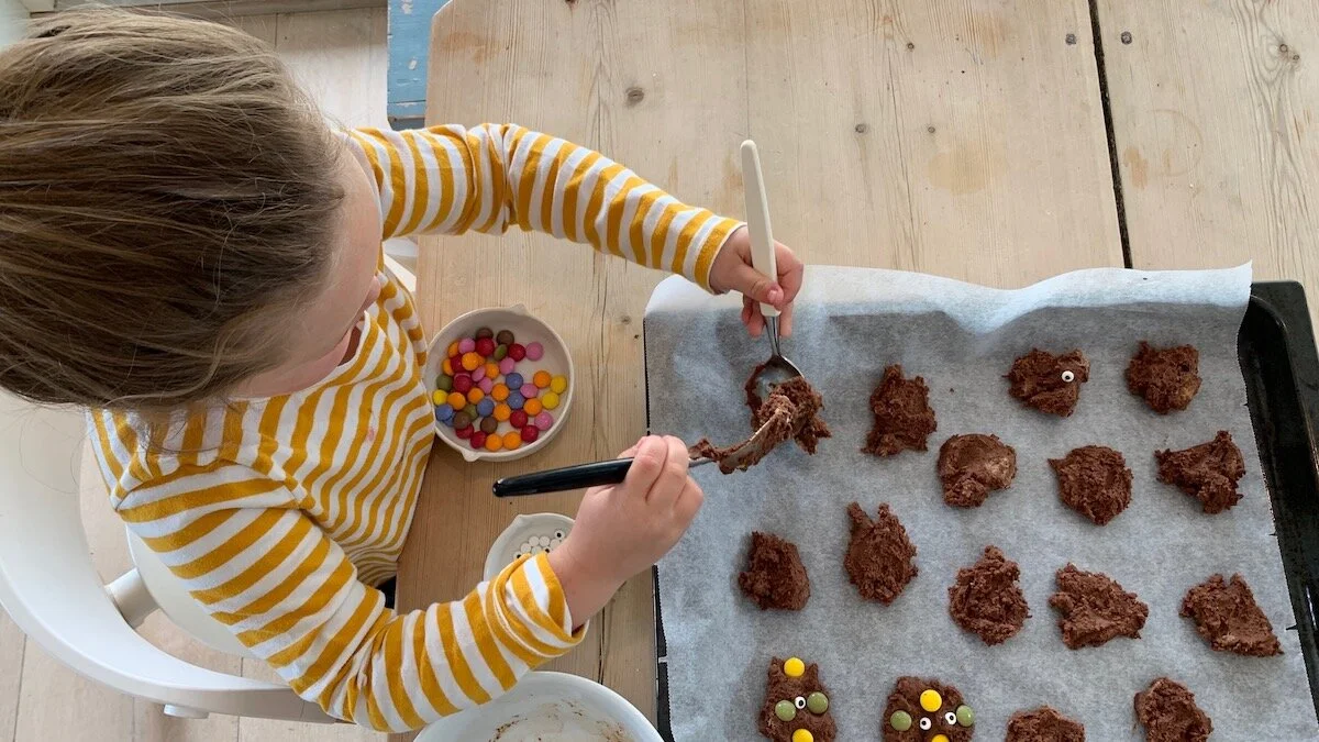 La barna være med å lage monsterkjeks. Hvis de er store nok til forme kjeksene kan de få hele ansvaret, hvis de trenger litt hjelp kan du forme kjeksene først og deretter overlate pyntingen med sjokoladeknapper og øyne til dem.