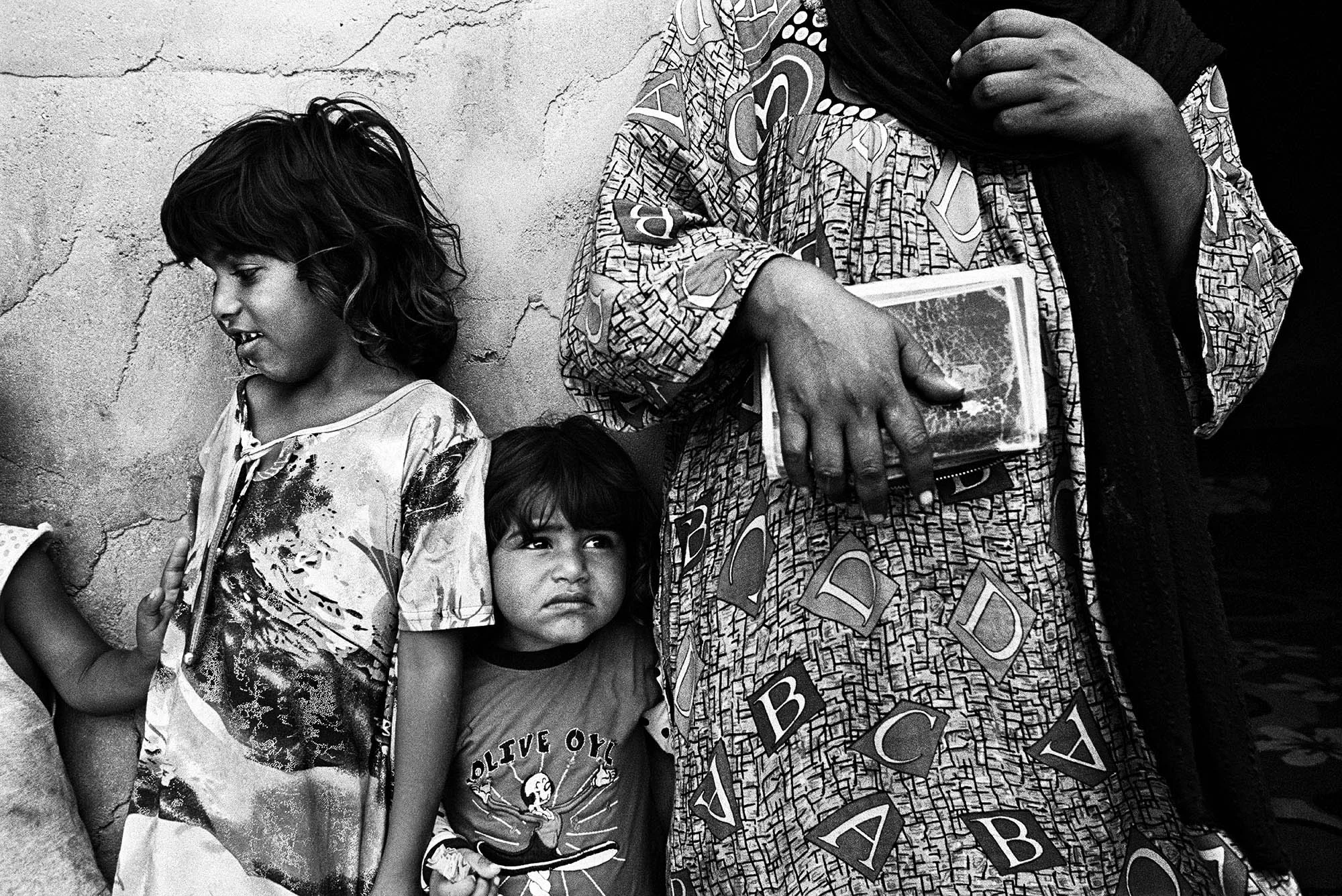 The Dom (gypsy) community are some of the most vulnerable people in Iraq. This 35-year-old woman holds her Iraqi nationality card and stands with her five and three-year-old daughters. None of her four children have documents. Many of the Dom throughout Iraq, were issued an Iraqi Nationality card with an special 'exception' stamp in it, which many authorities around the country now do not recognize as being legitimate.