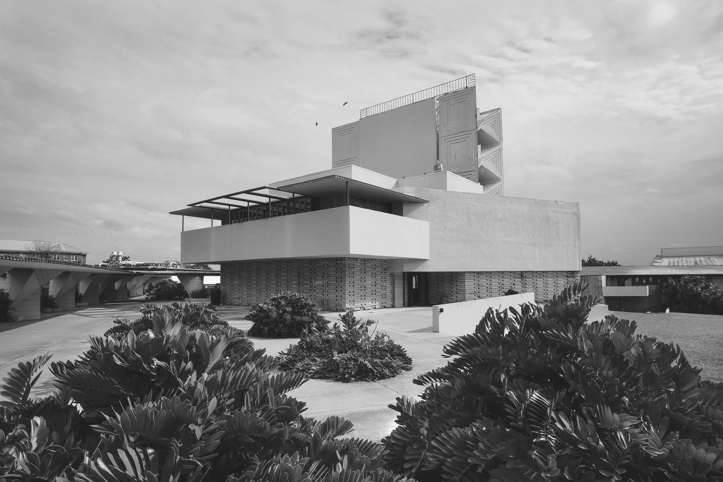 Black-and-white photograph of the Annie-Pfeiffer-Chapel by Frank Lloyd Wright architecture, tropical landscaping, and birds in the sky