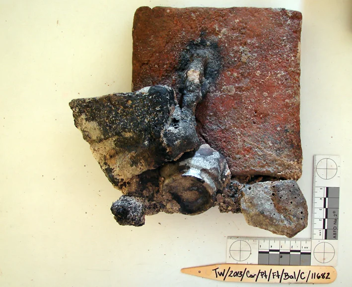 Yet another floor tile, this time with an iron concretion which has also stuck a base to a French faienceware beaker and some ballast chips and shells