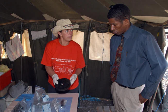 Kathy showing the wooden pulley wheel found on the site