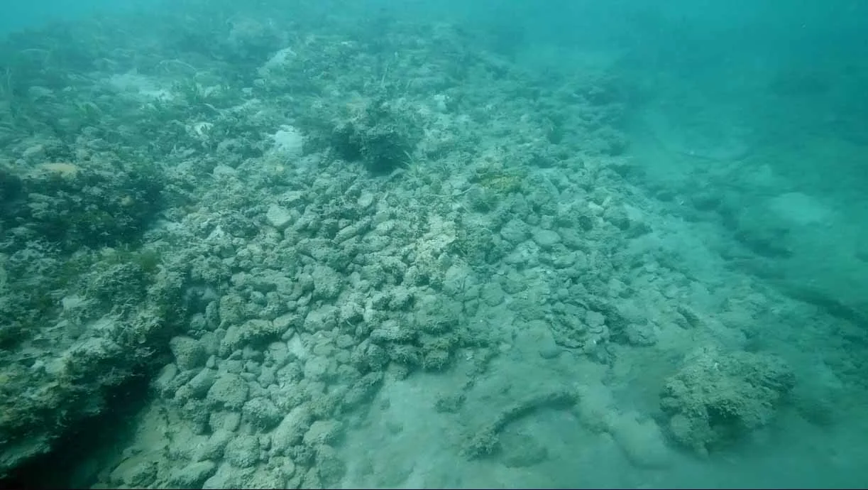 The ships stone ballast which had been swept off the hull in the storm and because the deck is tilting 20 drgrees down on the starboard side